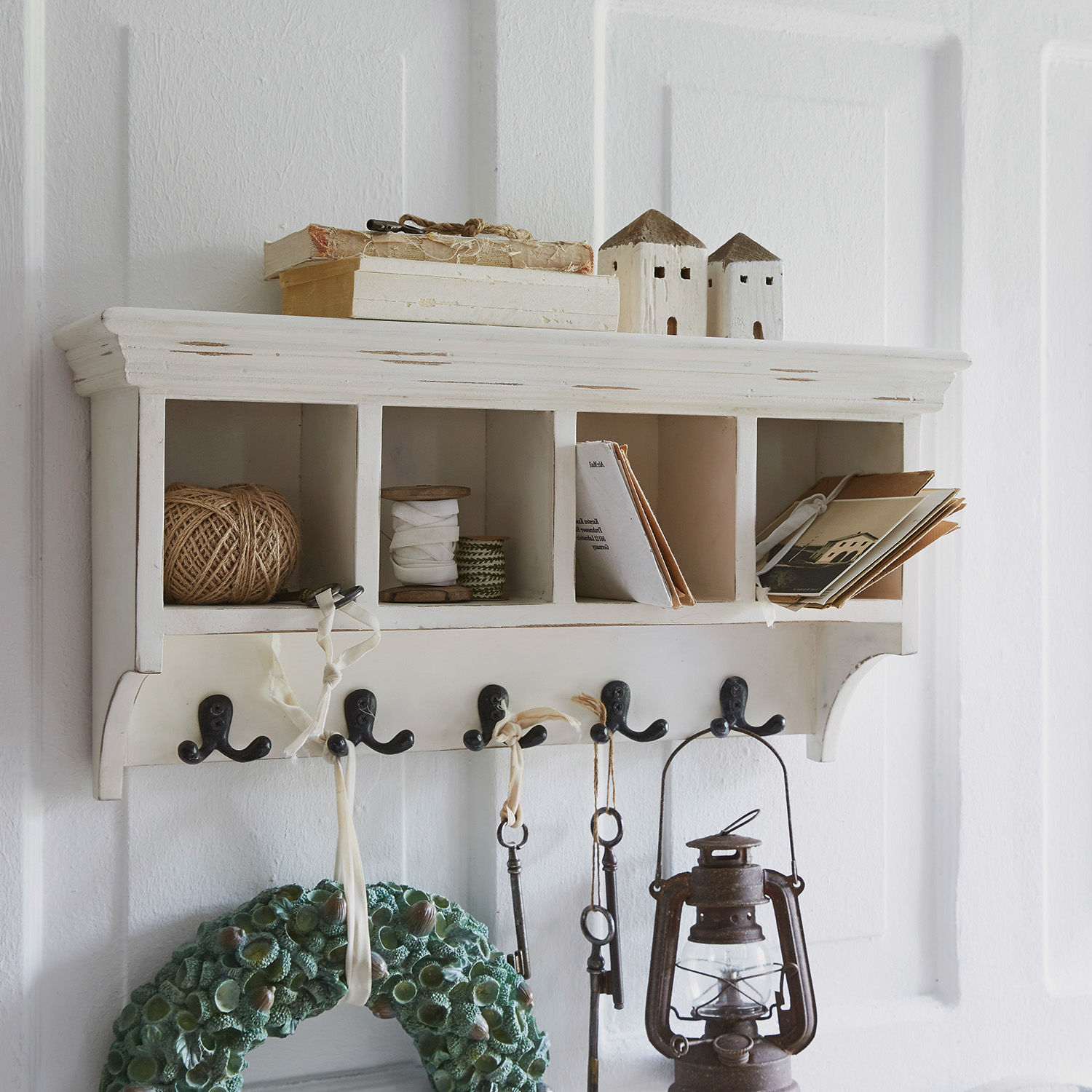 Witte houten wandkapstok met vakken en metalen haken voor sleutels en decoratie