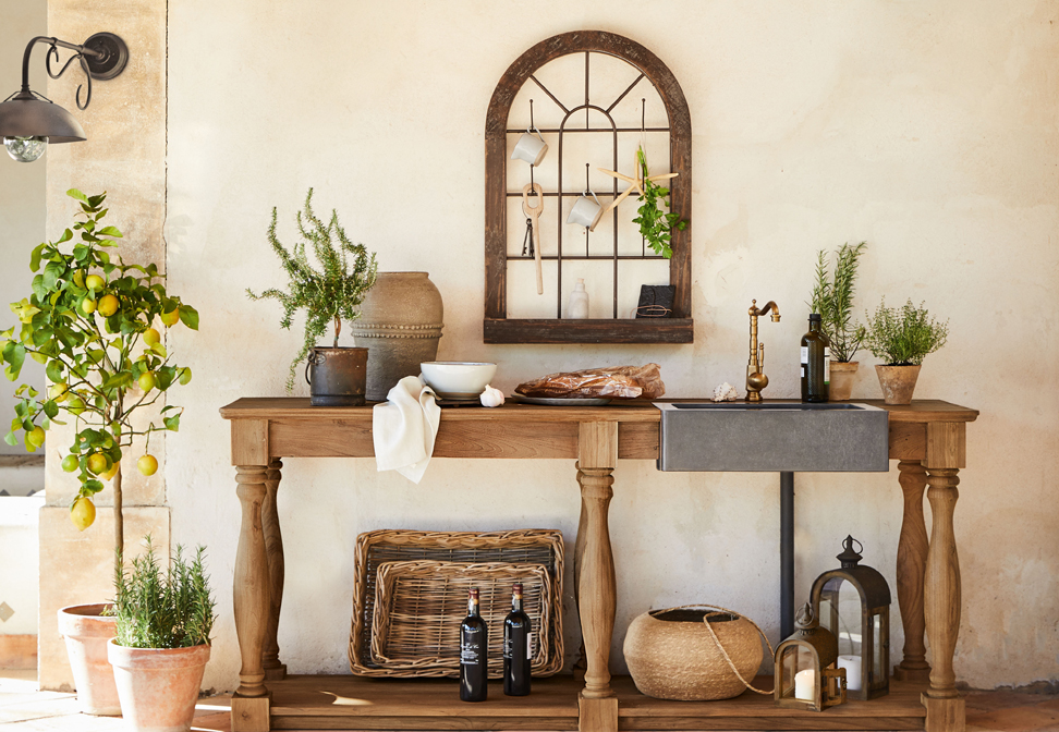 Houten tafel met betonnen gootsteen en koperen kraan in mediterrane stijl met planten en decoraties