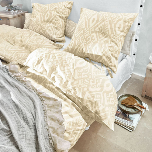 Beige beddengoed met geometrisch patroon van zachte stof op bed in lichte kamer