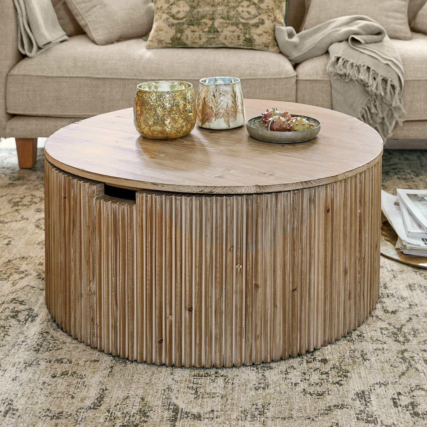 Ronde houten salontafel in natuurlijke kleur op tapijt bij beige bank met dekens