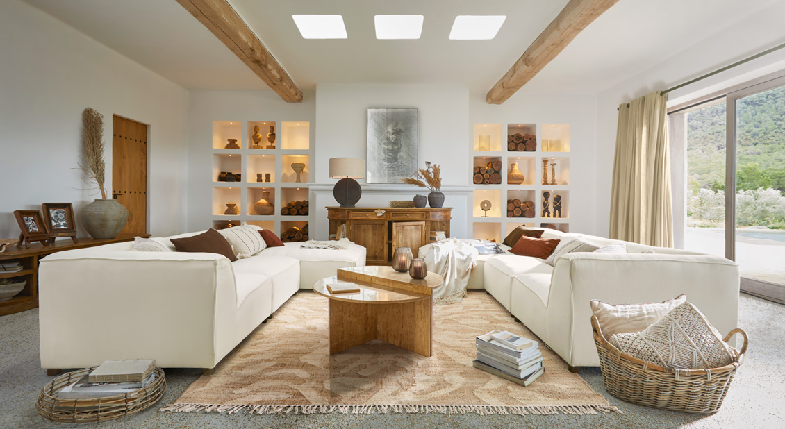 Ruime woonkamer met witte banken, houten tafel en natuurlijke decoraties in warme beige tinten