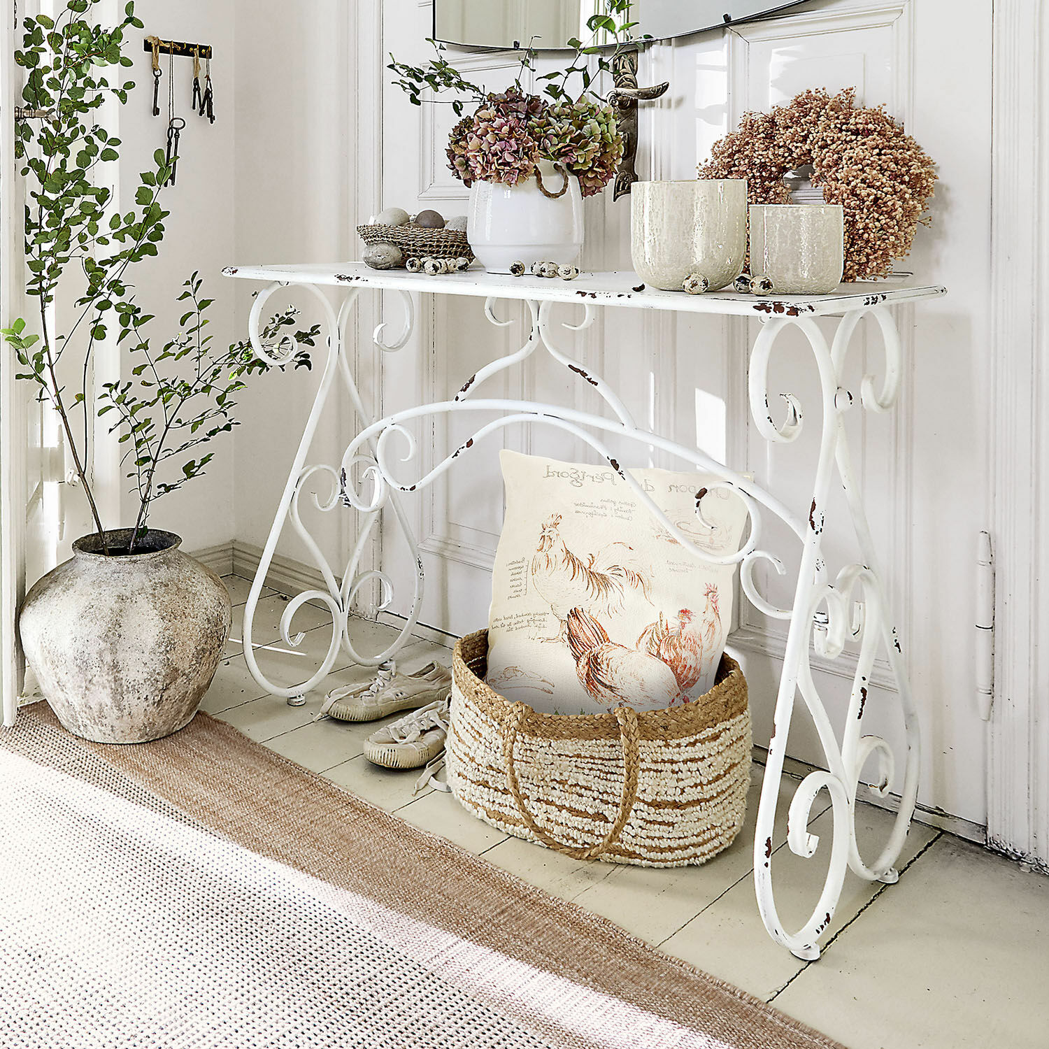 Sidetable Stonem Witte metalen tafel met decoratieve planten en rieten mand met kussen in rustieke stijl