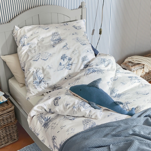 Katoenen beddengoed wit met blauwe zee-motieven op grijs bed met decoratief haai-kussen