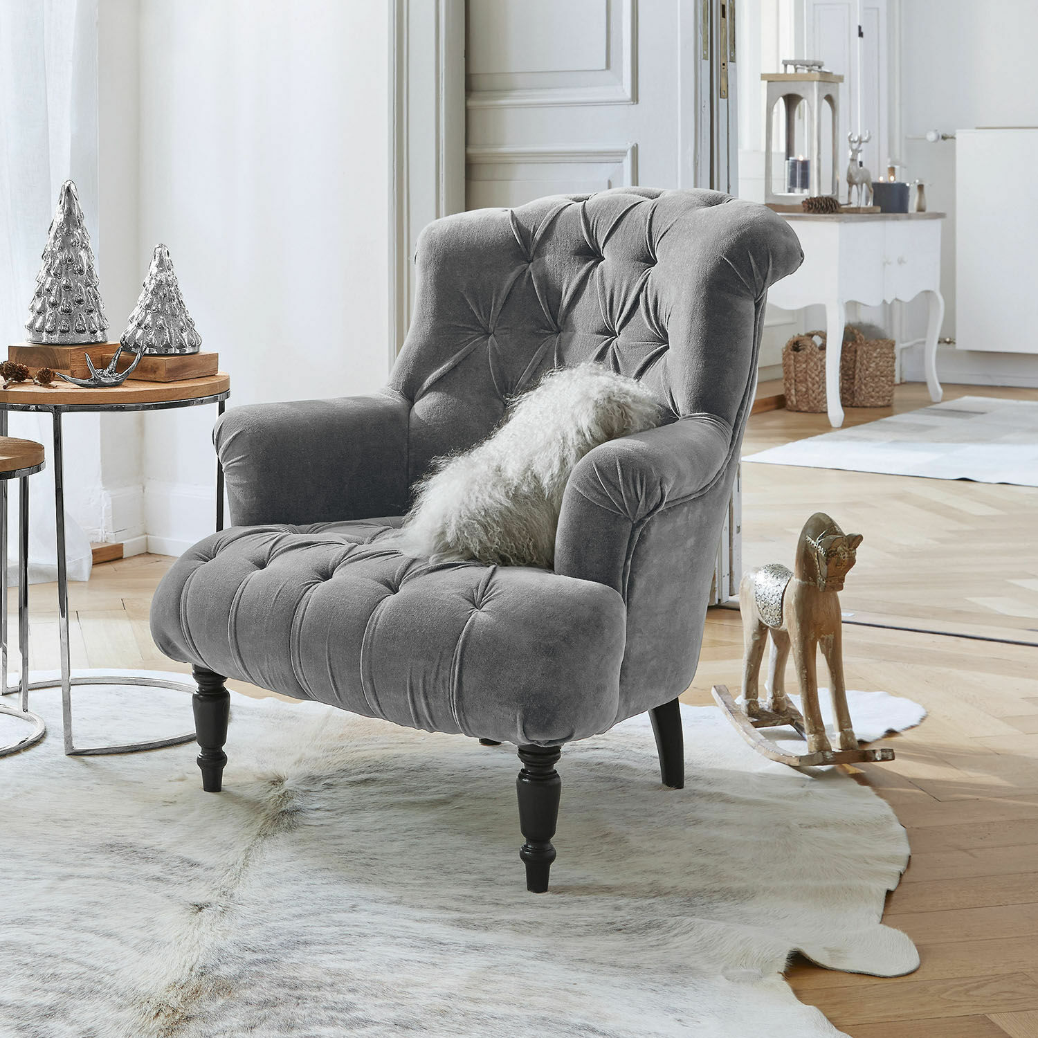 Fauteuil Parranquet Grijze fluwelen fauteuil met knoopstiksels en zwarte houten poten in lichte woonkamer met decoratie