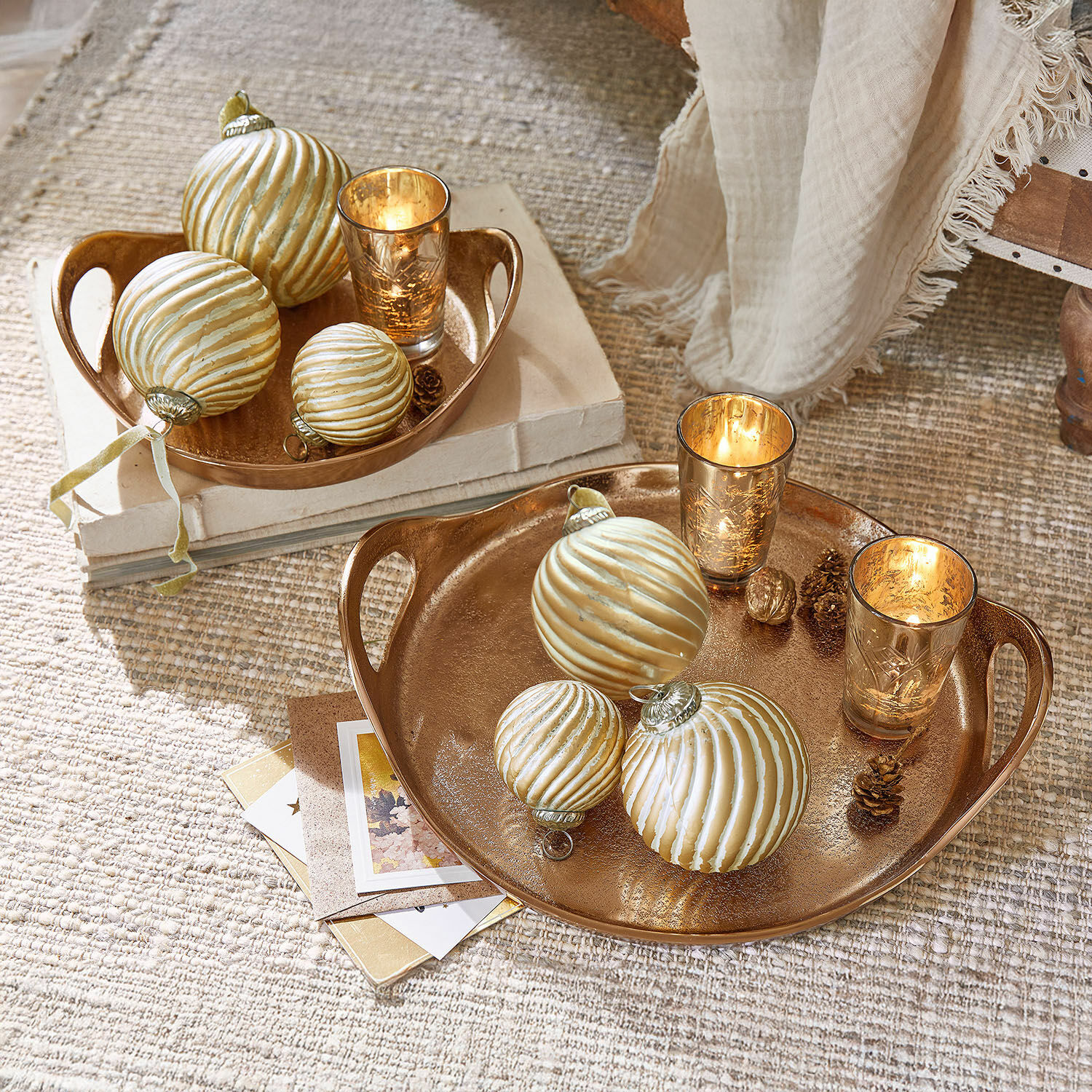 Gouden decoratieve schalen met kerstversiering en kaarsen op lichte vloer, sfeervolle woondecoratie