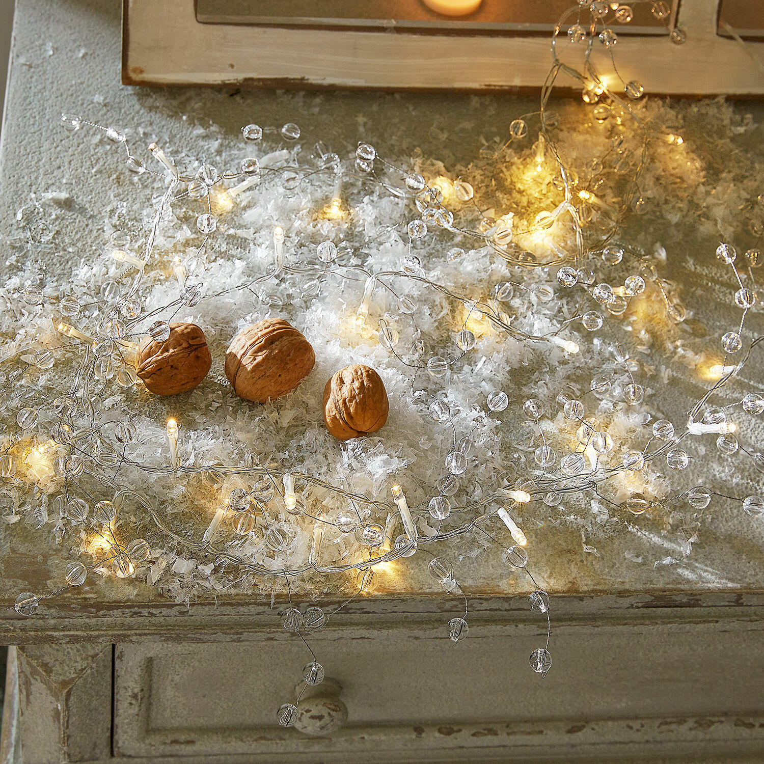 Lichtsnoer set van 2 Neviane Fijne LED-lichtsnoer met transparante kralen op rustieke tafel met decoratieve walnoten