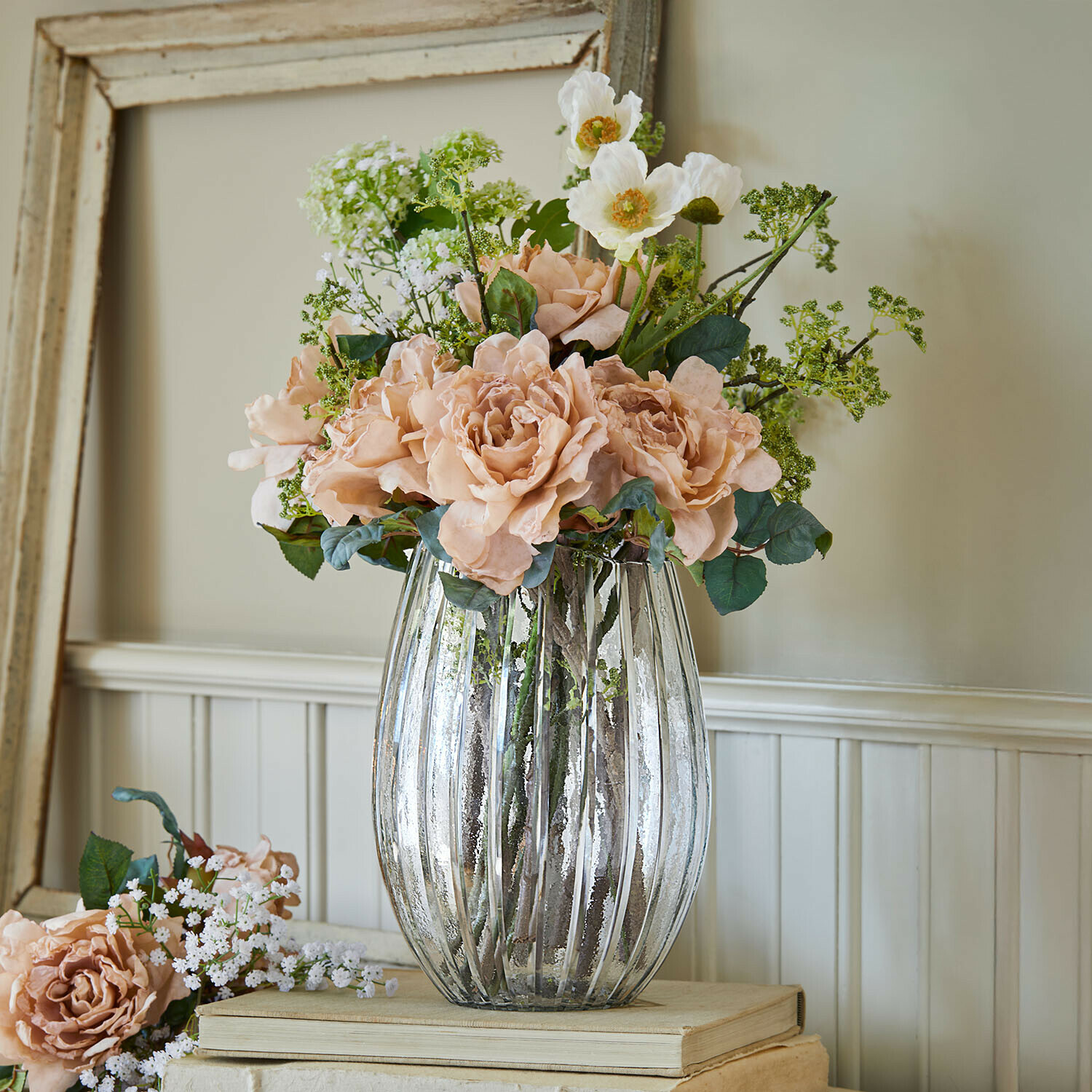 Glazen vaas met verticale ribbels en boeket van roze en witte decoratieve bloemen op houten ondergrond