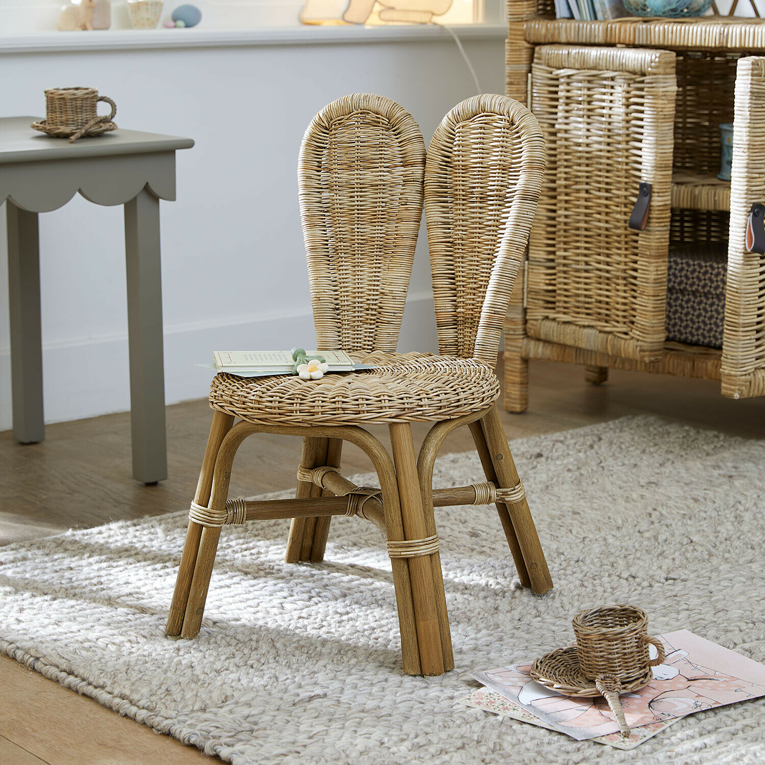 Kinderstoel van natuurlijk riet op een lichte vloerkleed in een kinderkamer