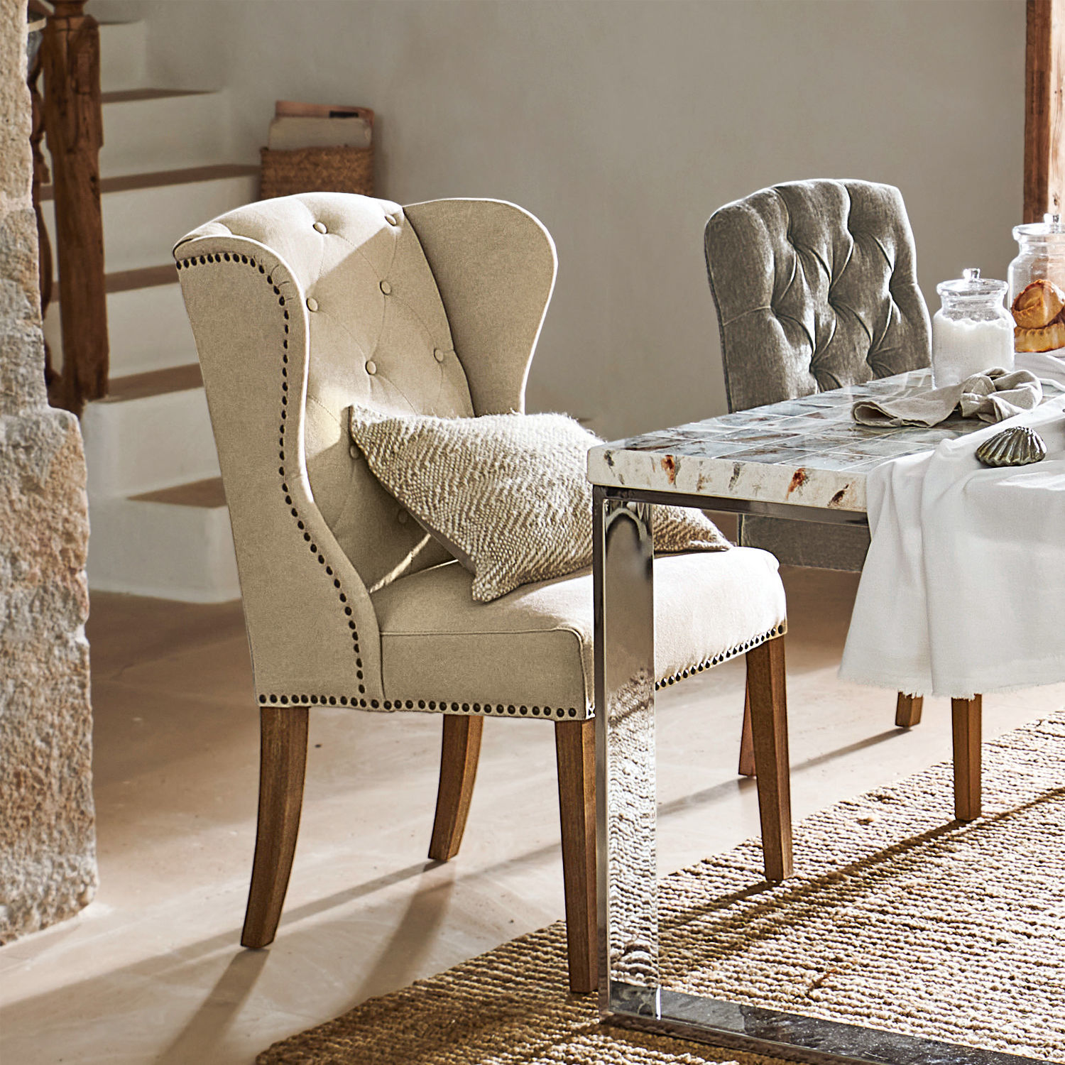 Beige gestoffeerde stoel met houten poten bij eettafel met stenen blad