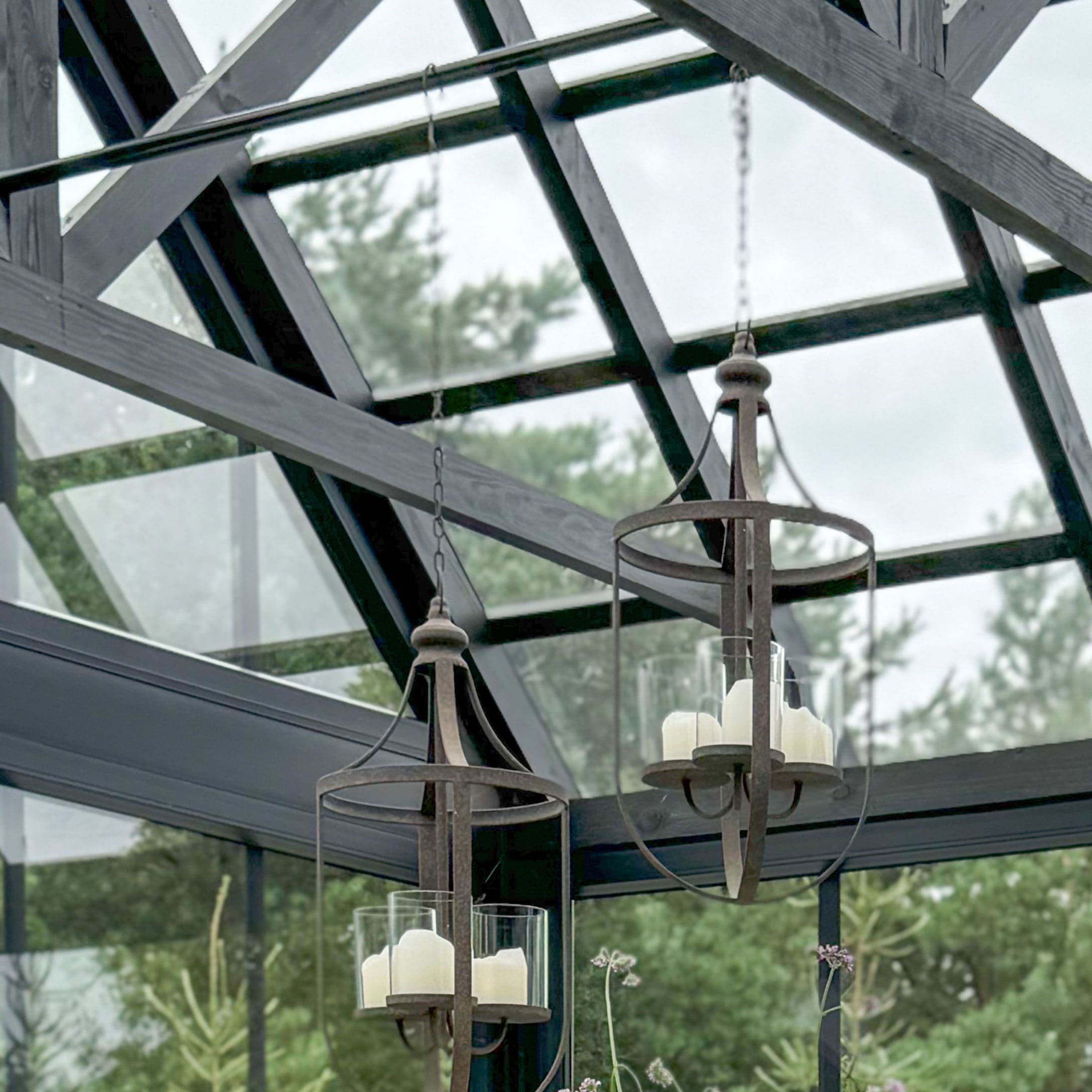Hangende lantaarns van roestig metaal met witte kaarsen, decoratie voor tuin of kas