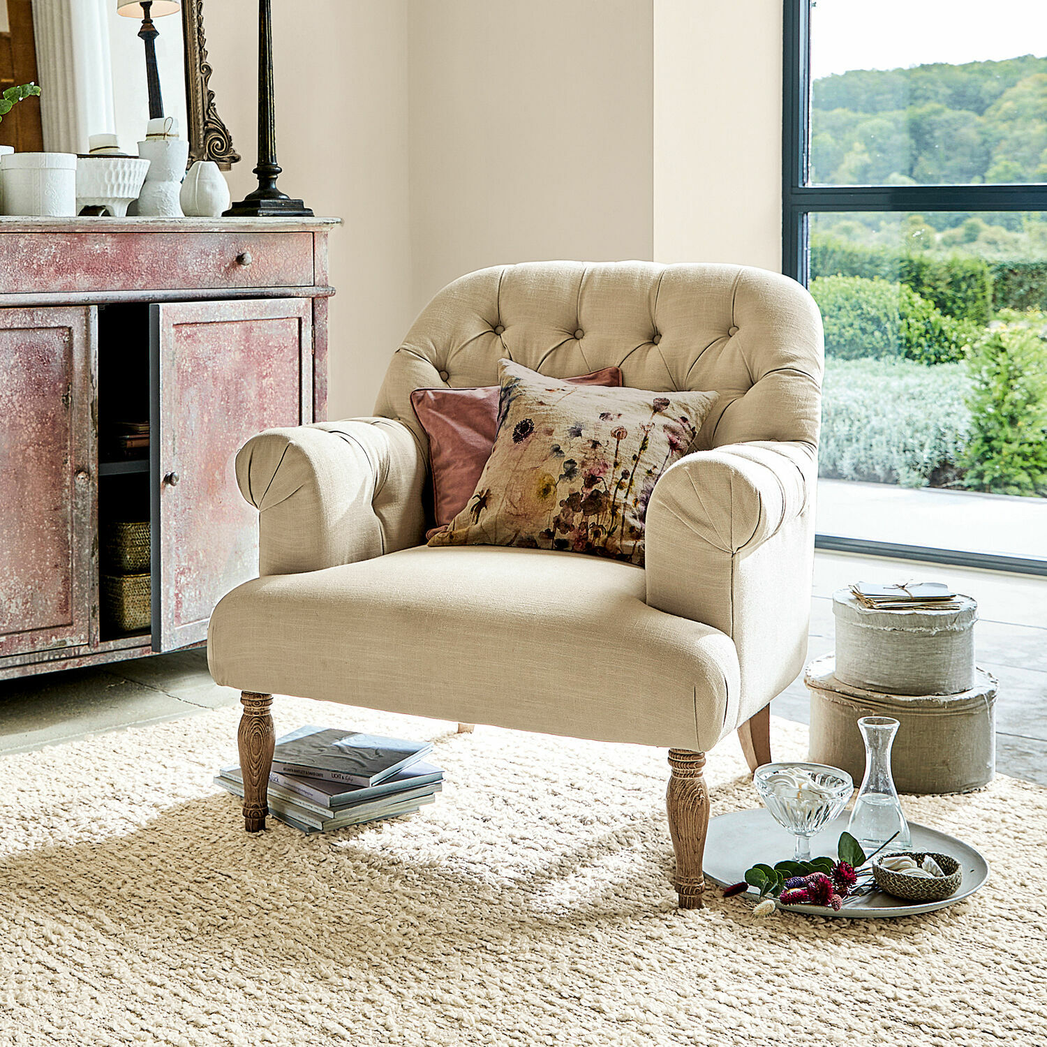 Fauteuil Shambrook Beige gestoffeerde fauteuil met houten poten en decoratieve kussens in lichte woonkamer