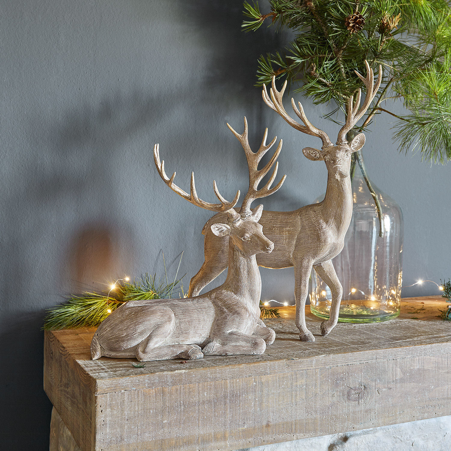 Hert set van 2 Barima Twee decoratieve houten hertenfiguren in natuurlijke kleur op een houten blad met groene takken