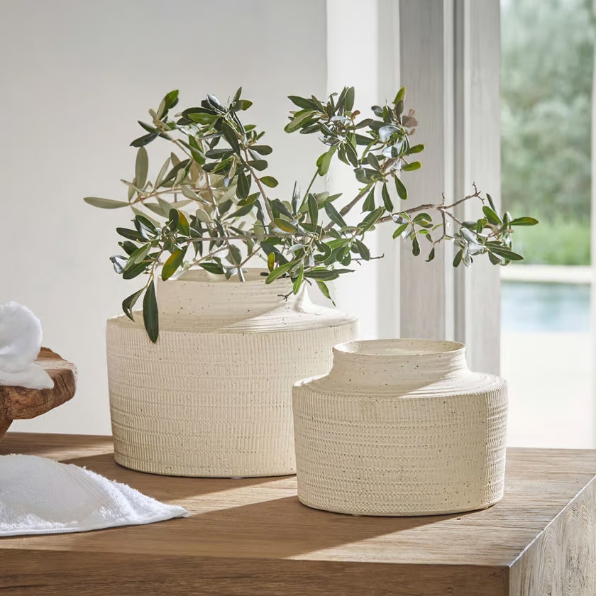 Twee crèmekleurige keramische vazen met structuur op houten tafel met groene takken