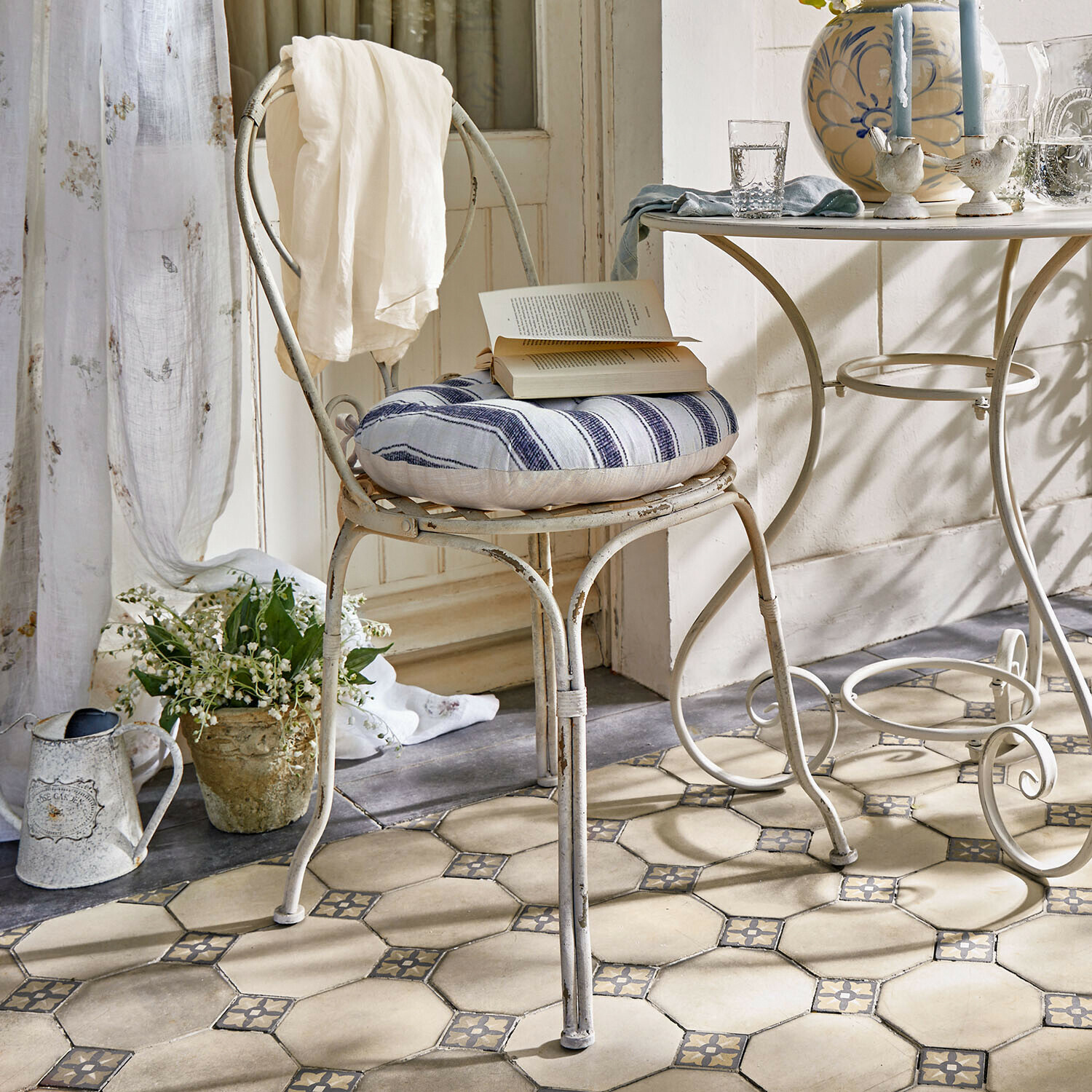 Stoel Aube Vintage metalen stoel met blauw-wit gestreept kussen en witte doek over de rug in lichte kamer