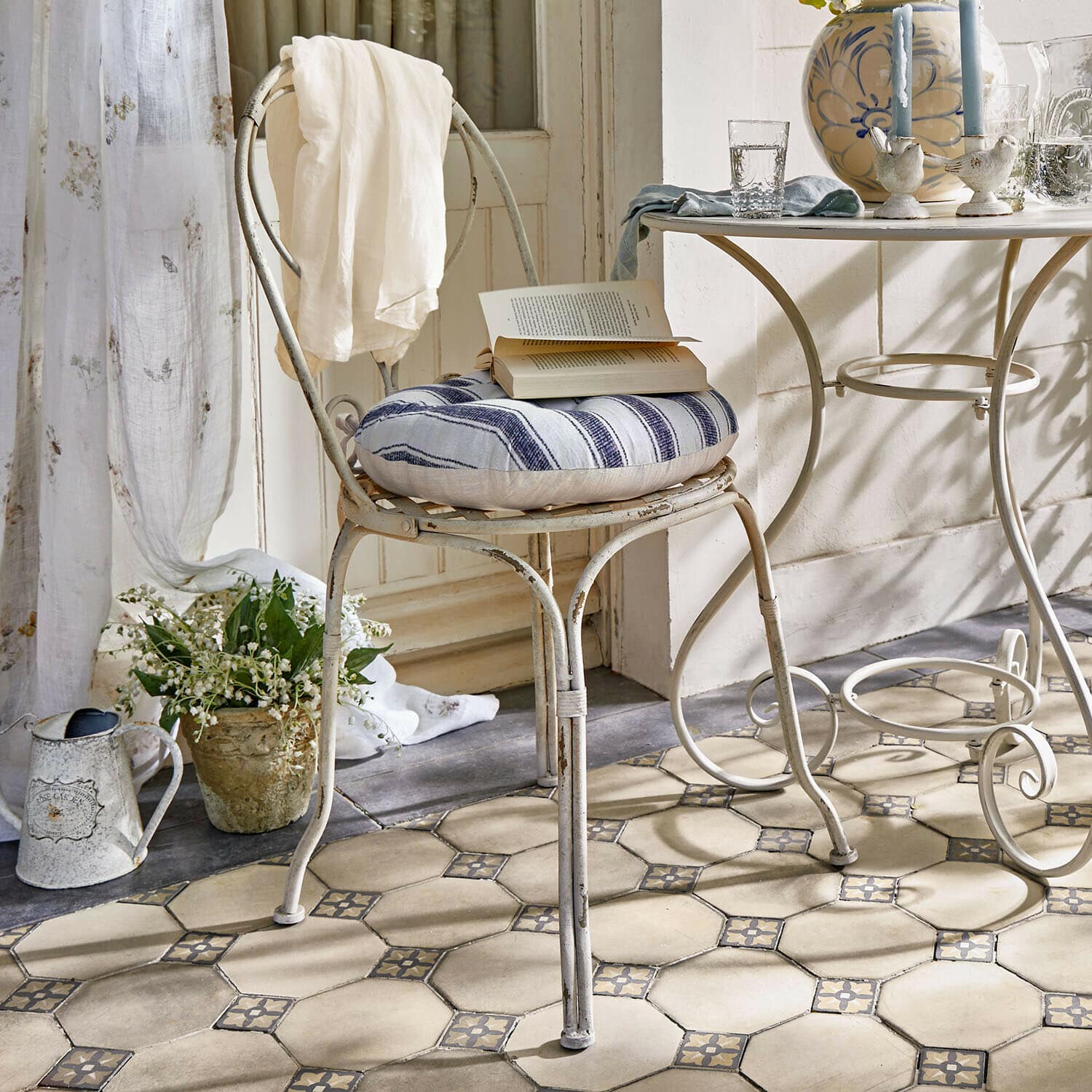 Stoel Aube Vintage metalen stoel met blauw-wit gestreept kussen en witte doek over de rug in lichte kamer
