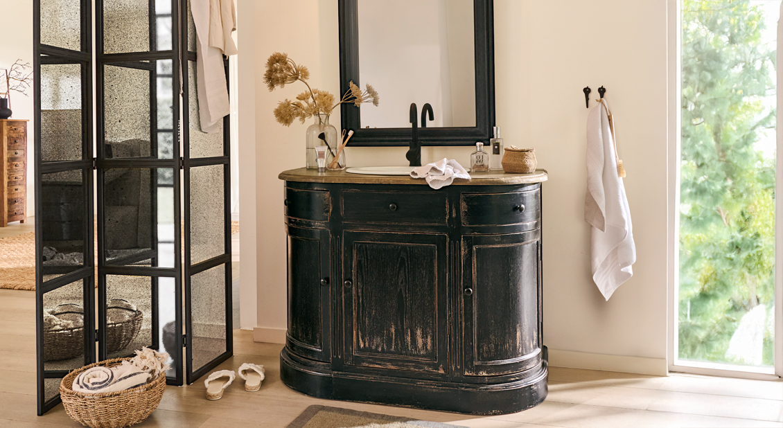 Zwarte houten badkamerkast met wastafel en spiegel in lichte, natuurlijke ruimte
