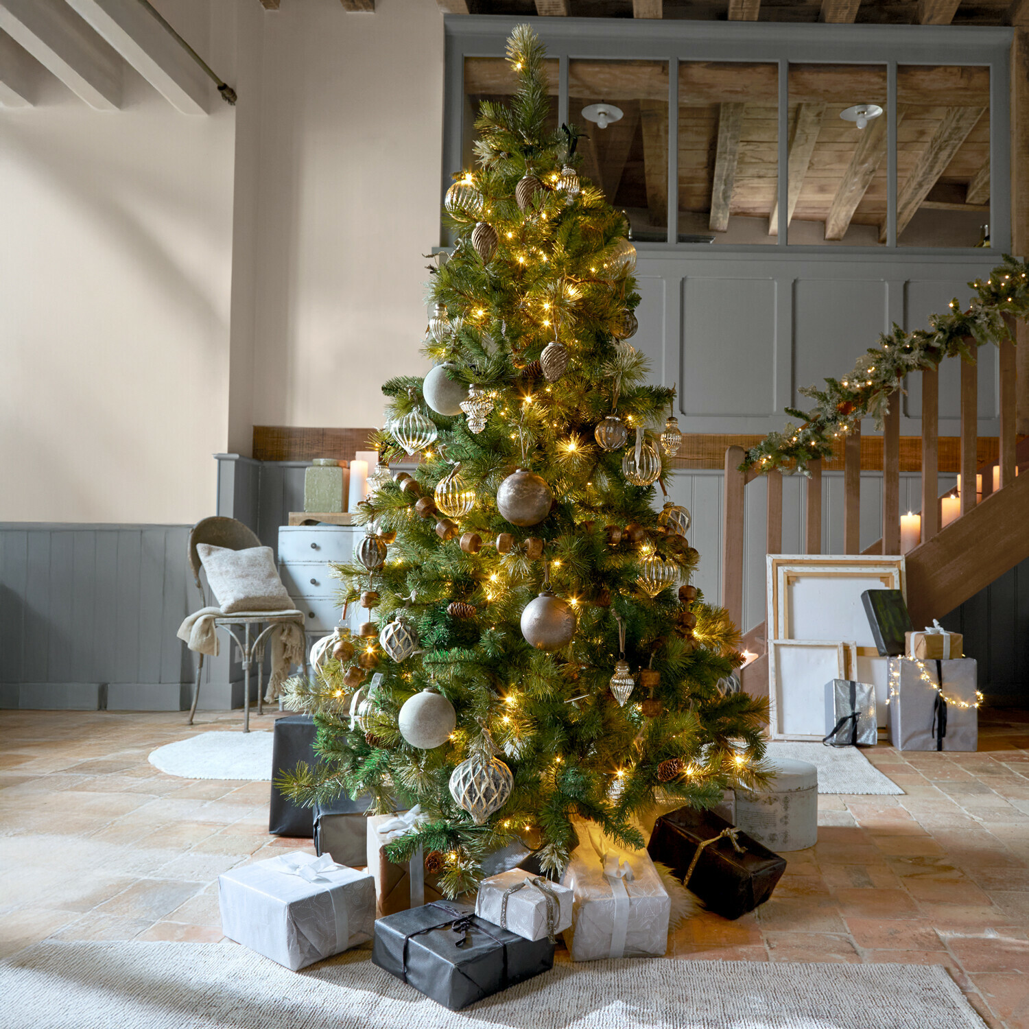 Kerstboom Aure Versierde kerstboom met groene takken en gouden lichtjes in een gezellige kamer met cadeaus