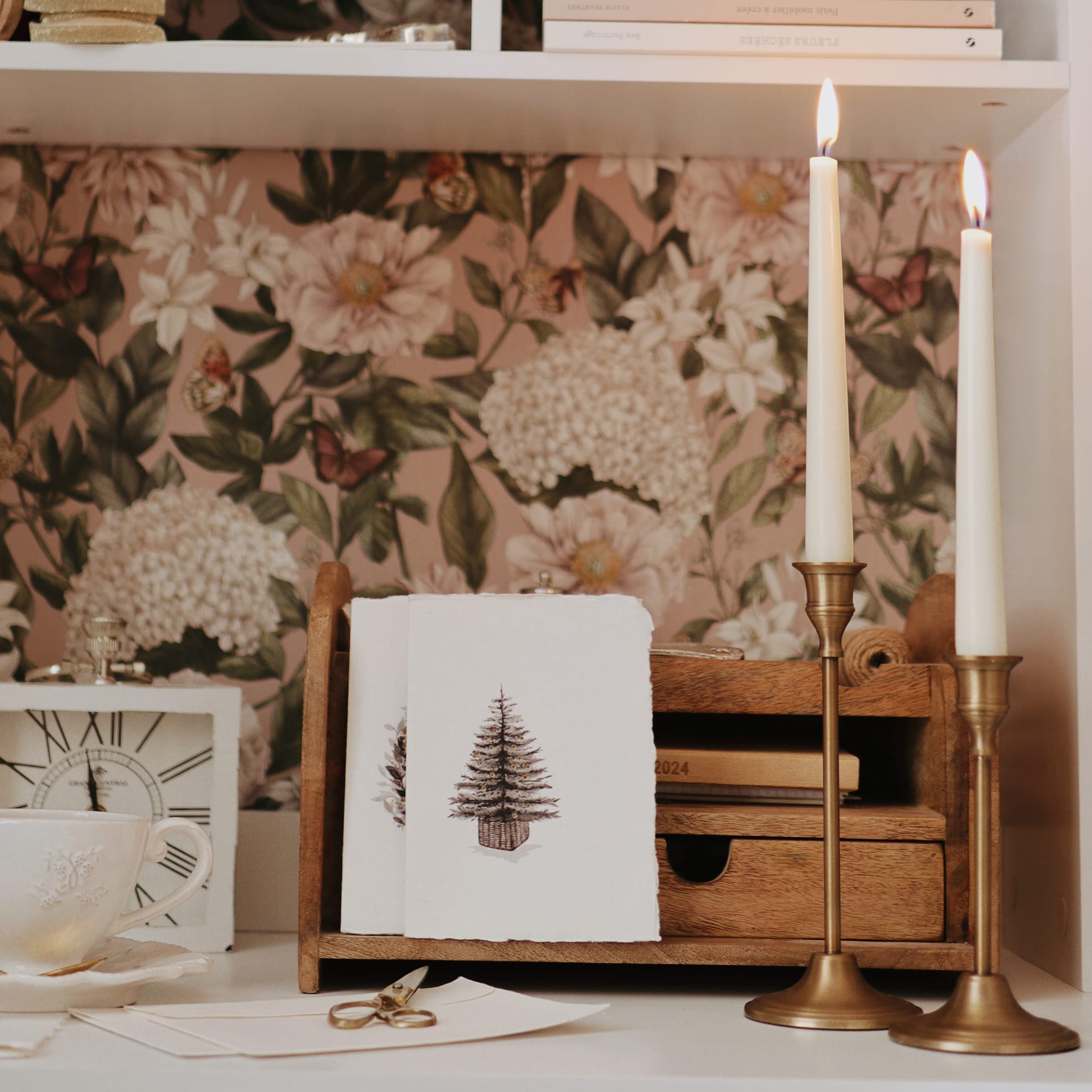 Houten organizer met kerstkaarten, brandende kaarsen en kopje voor bloemenbehang