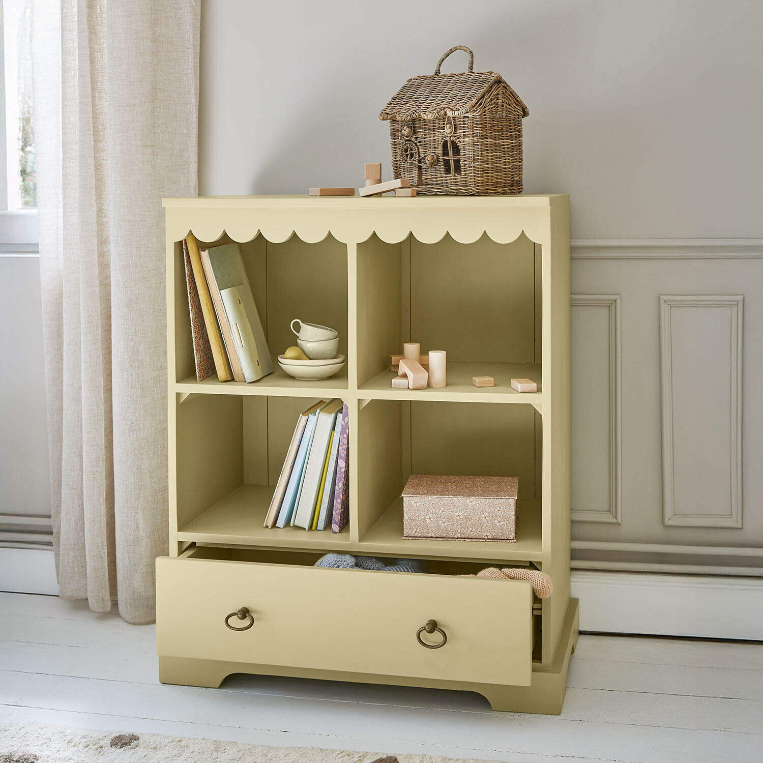 Beige houten kast met vier vakken en lade, decoratieve rieten mand bovenop