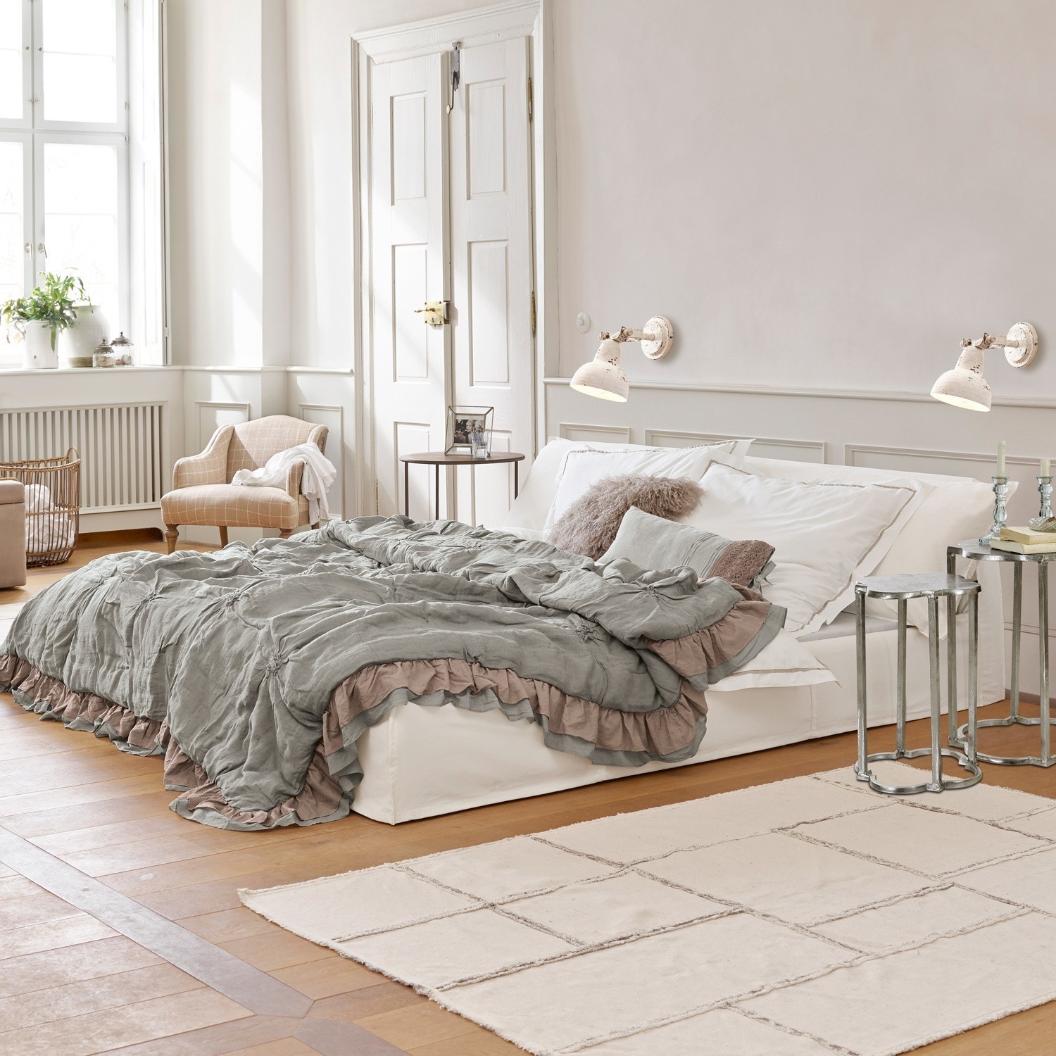 Bed Cottonwood Gezellige slaapkamer met wit bed en grijsgroene deken met ruches op lichte houten vloer