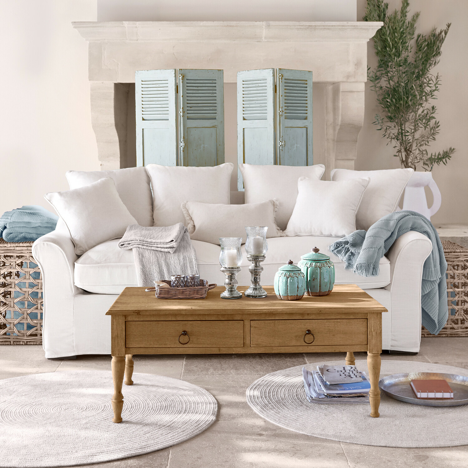 Beige bank met kussens en houten salontafel met decoraties in lichte woonkamer met open haard