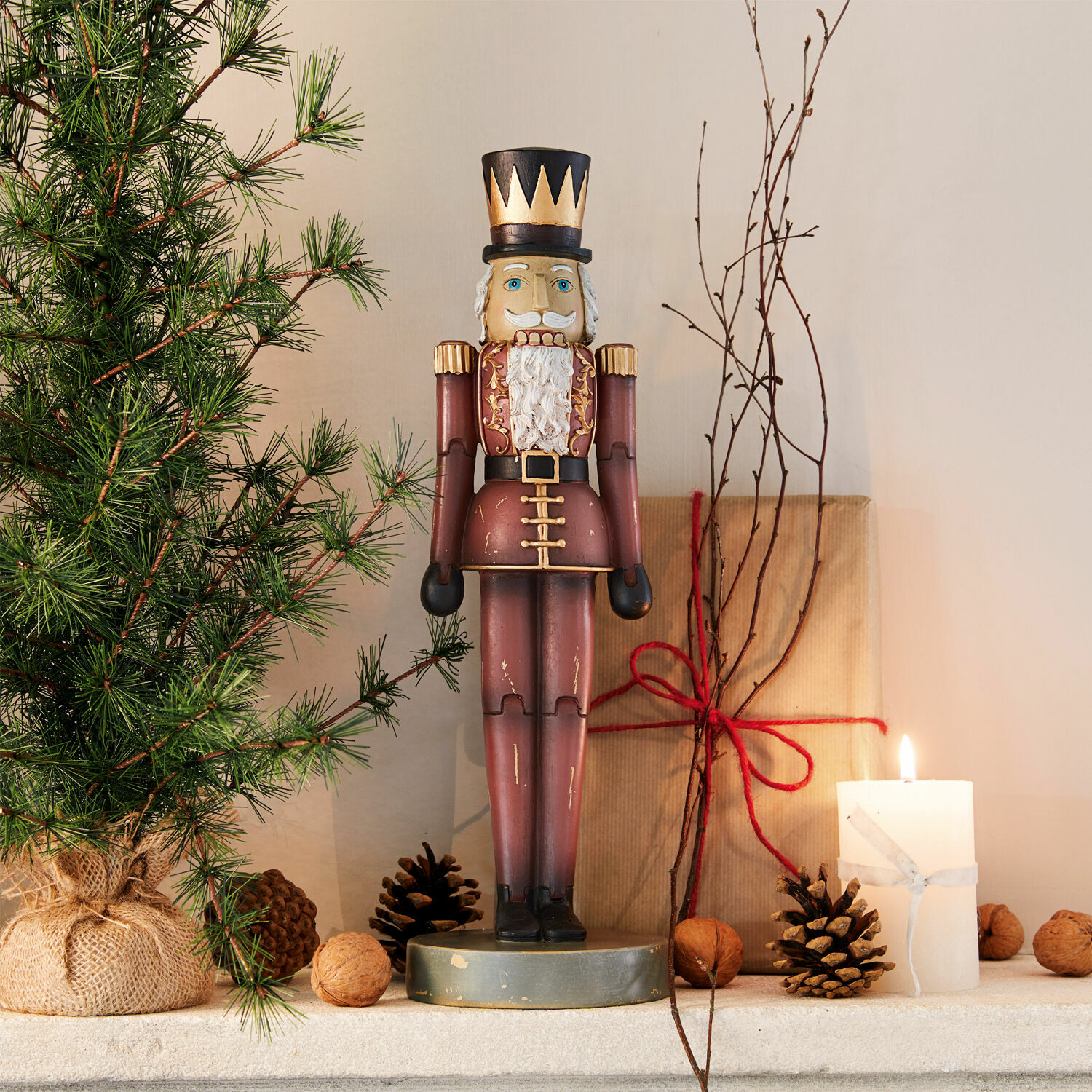 Siernotenkraker Serifa Houten notenkraker in bordeauxrode uniform met zwarte hoed, kerstdecoratie met dennentak en brandende kaars