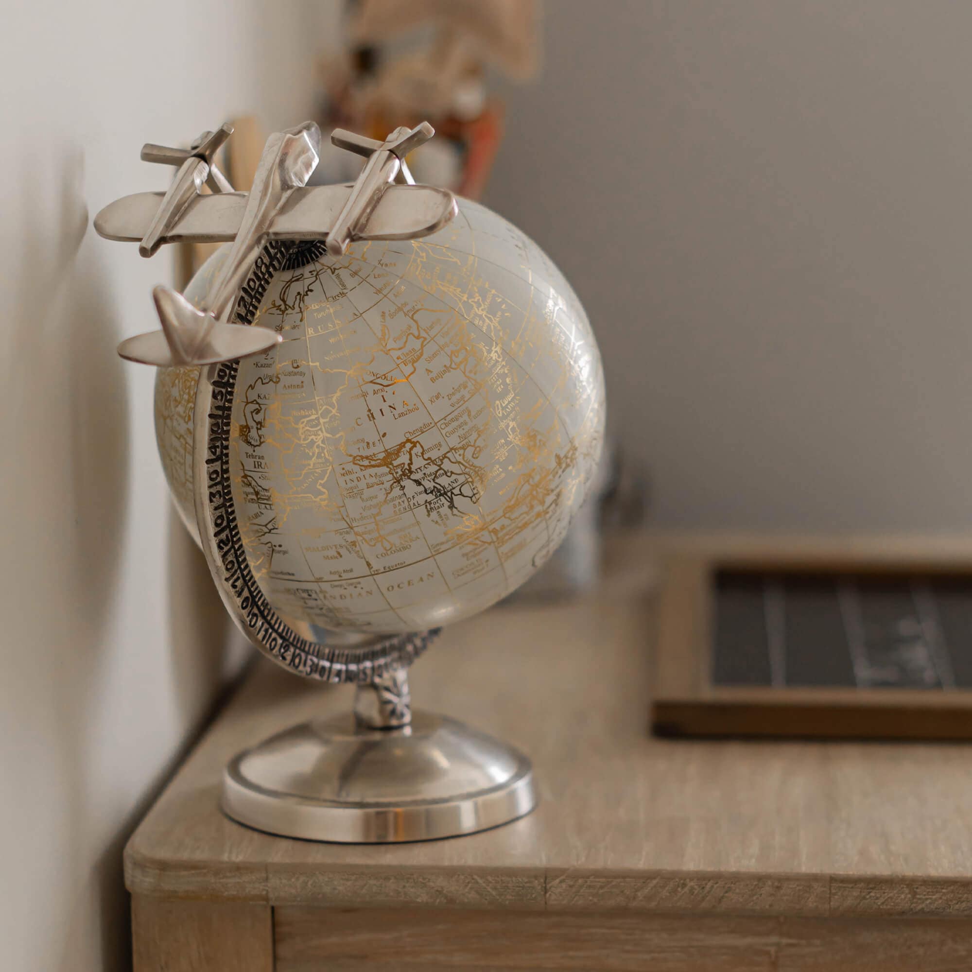 Decoratieve zilveren wereldbol met metalen vliegtuig op houten bureau, stijlvolle decoratie