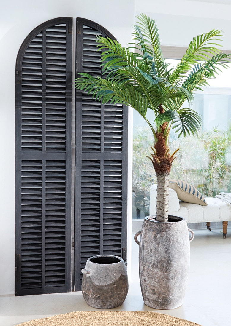 Grote en kleine grijze keramische pot met groene kunstpalm in lichte woonkamer