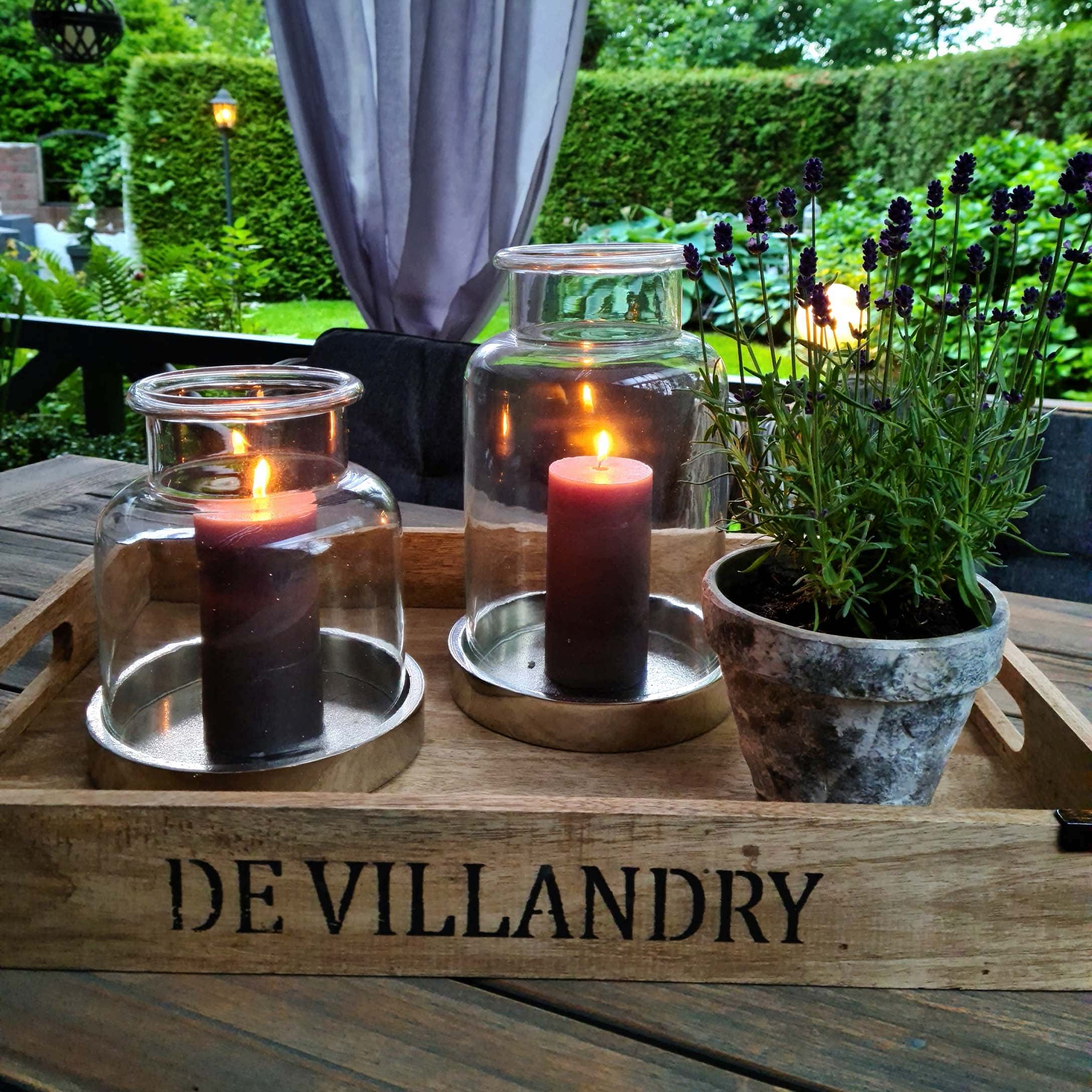 Houten dienblad met twee glazen lantaarns en een lavendelpot op houten tafel in tuin
