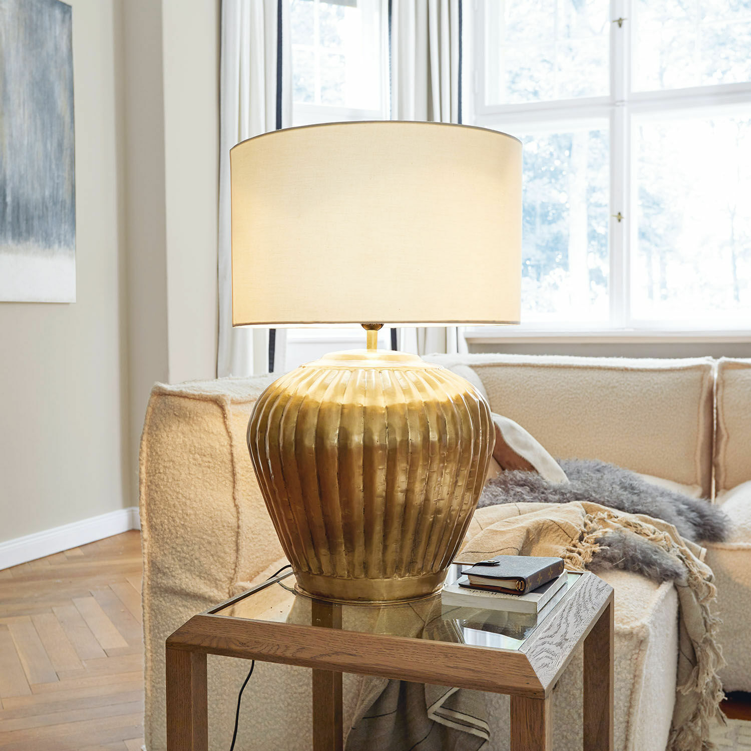 Tafellamp Fauville Gouden metalen tafellamp met beige kap op glazen tafel in lichte woonkamer