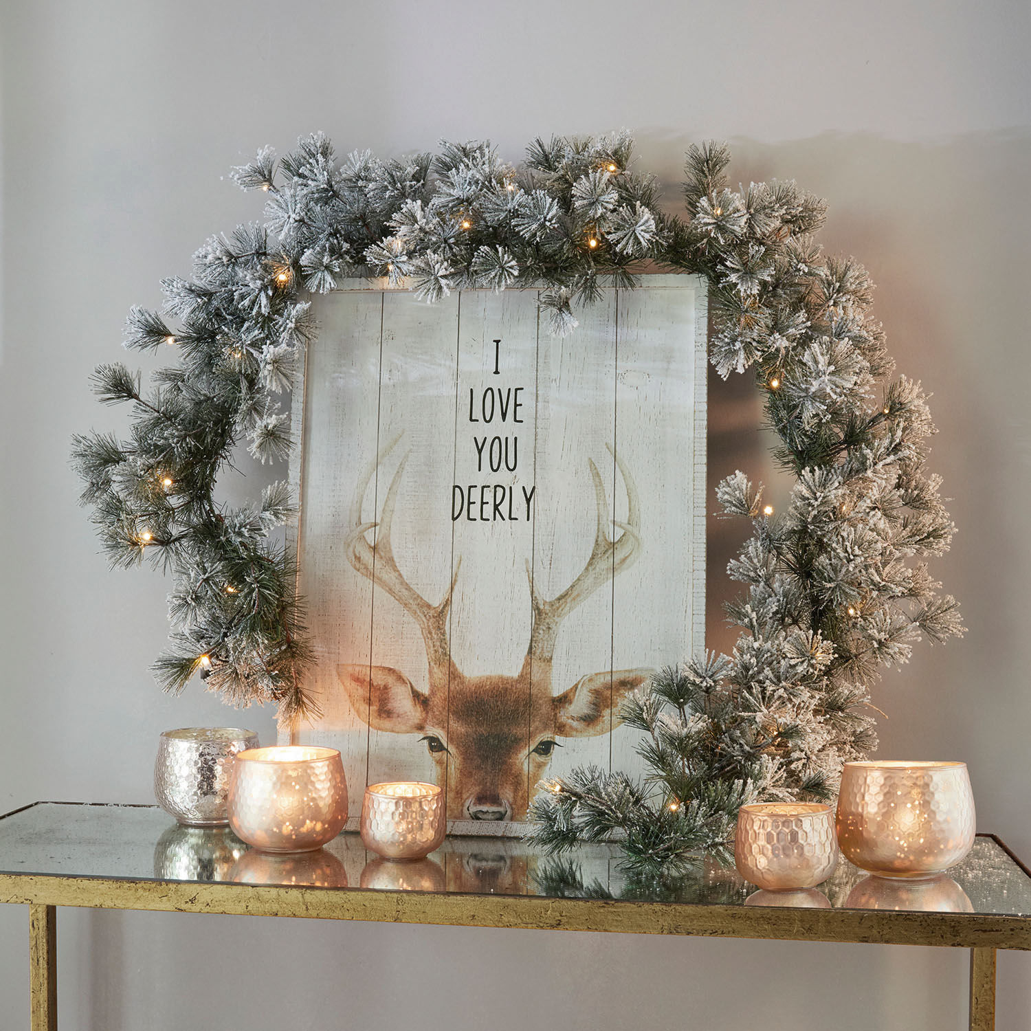 Guirlande Toni Decoratieve sneeuwkrans met LED-lichtjes op gouden tafel met brandende kaarsen