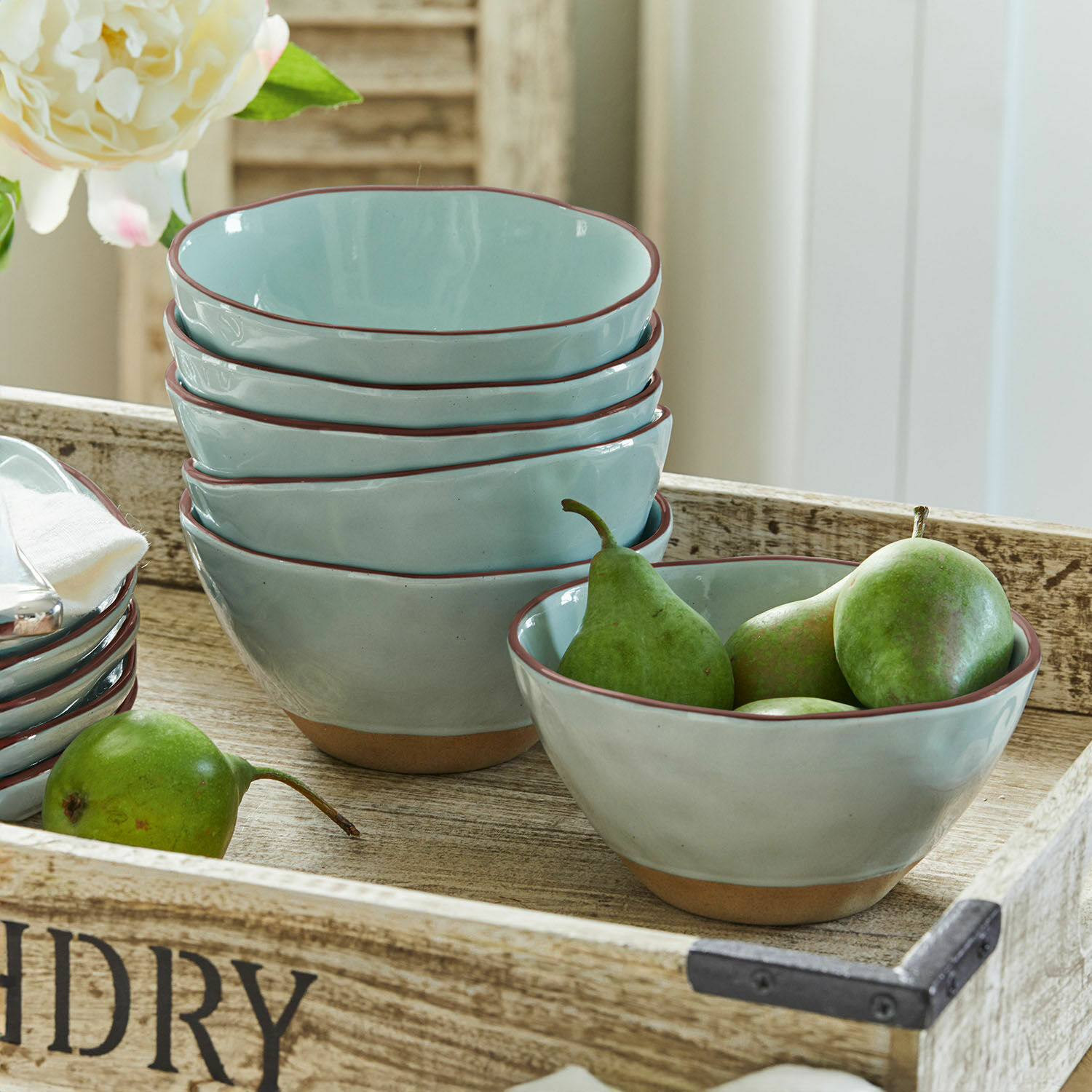 Set lichtblauwe keramische kommen met bruine rand op houten dienblad met peren