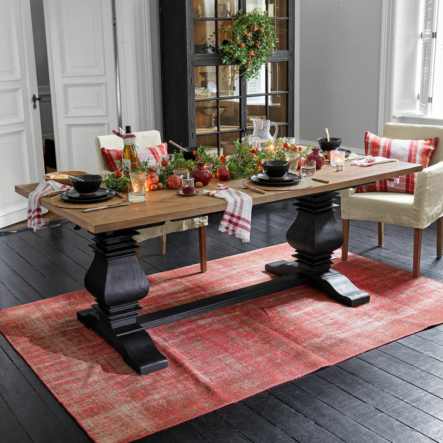 Tafel Quillancourt Eettafel met houten blad en zwarte poten op rood vloerkleed, feestelijke decoratie met kaarsen