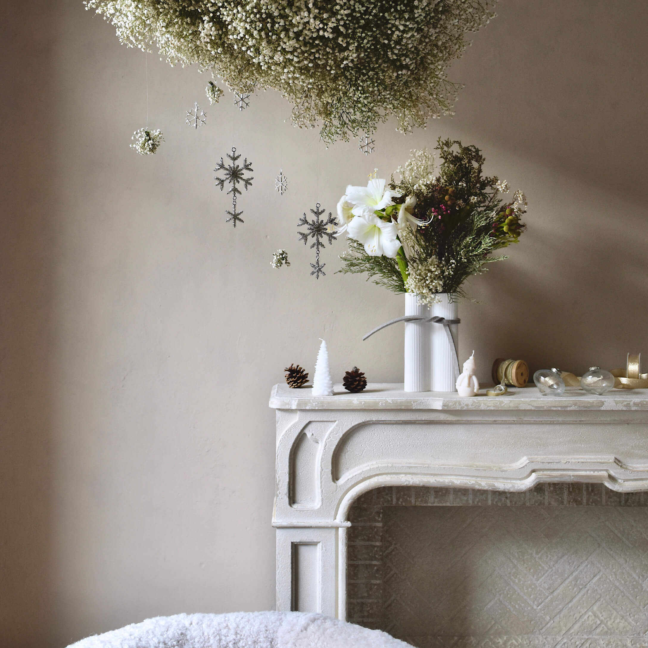 Witte decoratieve open haard met vaas en bloemen, kerstdecoraties met dennenappels en kaarsen