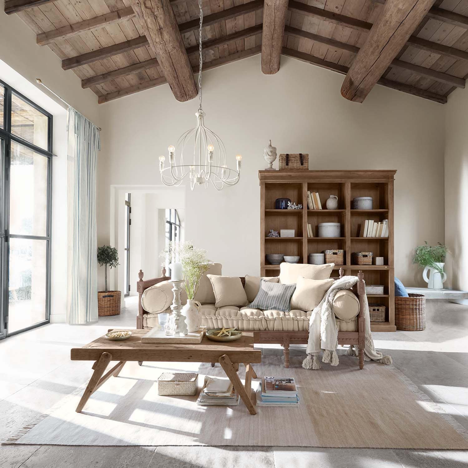 Gezellige woonkamer met houten tafel en beige bank onder houten balkenplafond