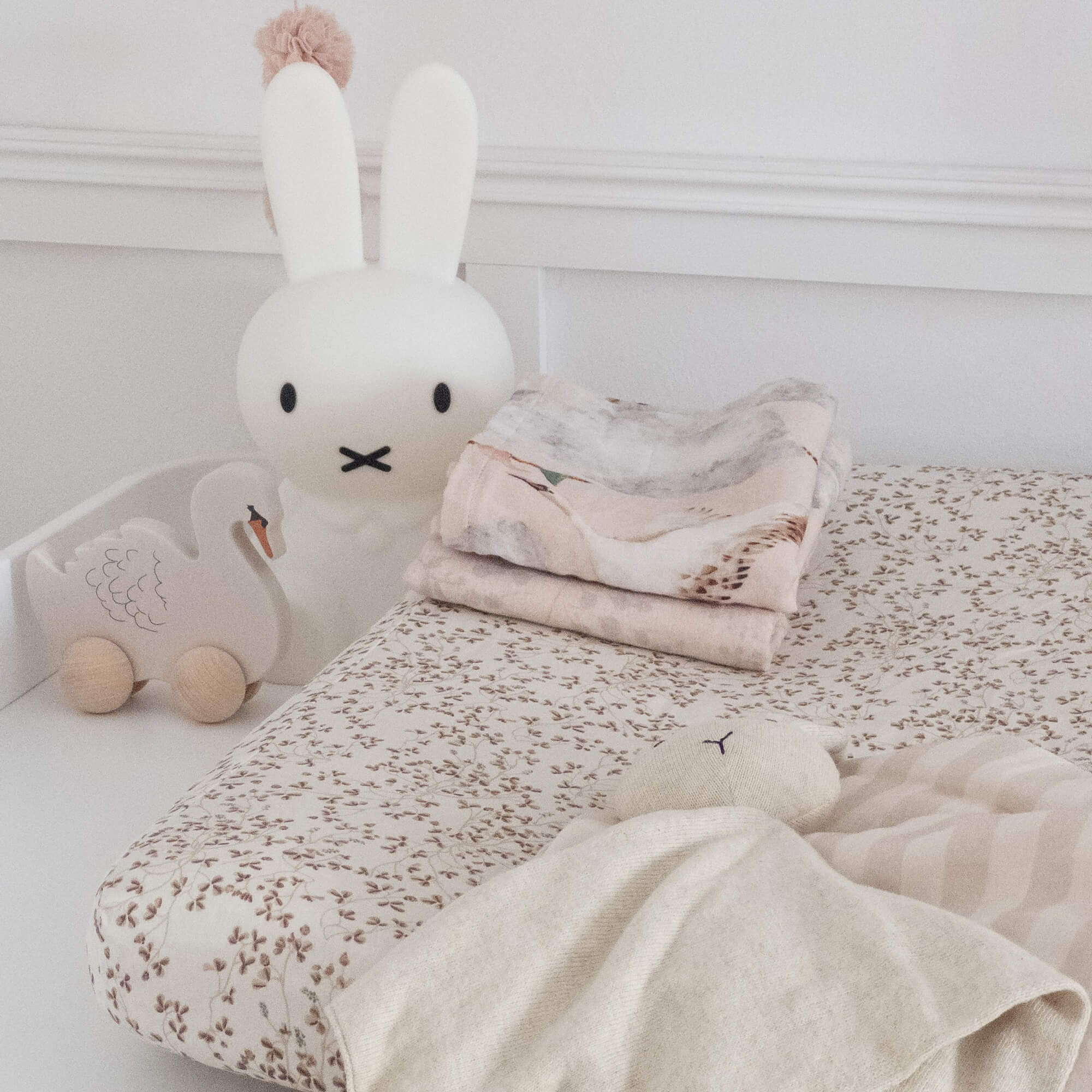Kinderbed met licht bloemenbeddengoed en zachte konijnenknuffel in neutrale tinten