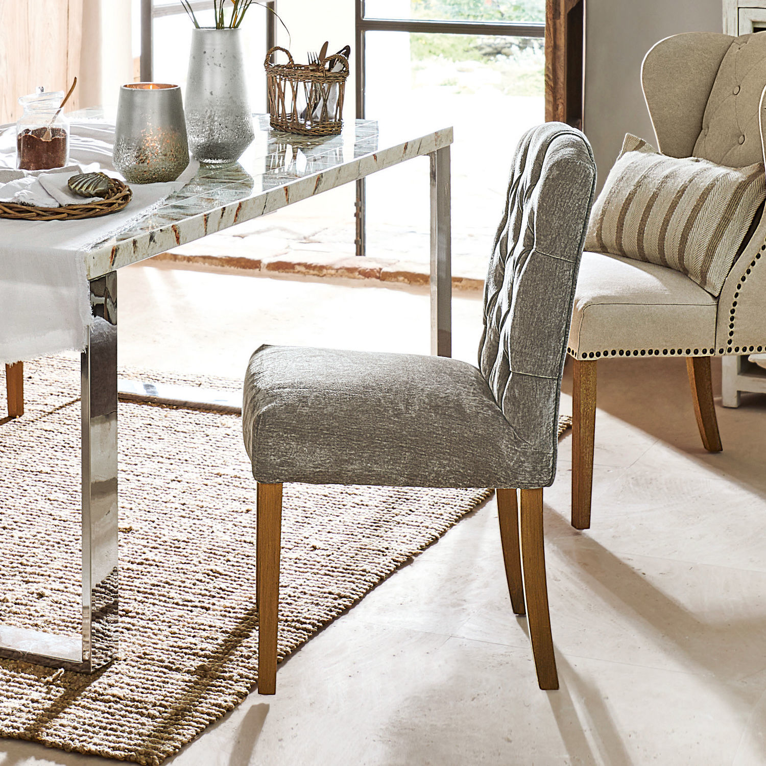 Grijze gestoffeerde stoel met houten poten bij een marmeren tafel in de eetkamer