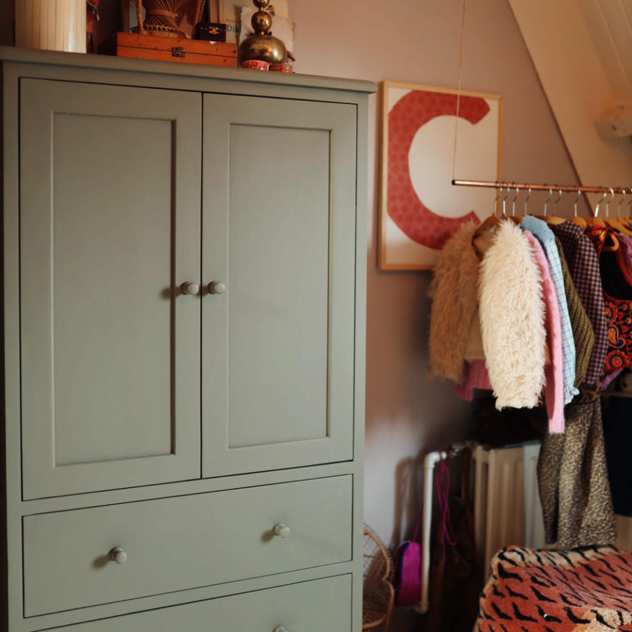 Grijze houten kast met twee lades in een gezellige kamer met kleding aan de kapstok