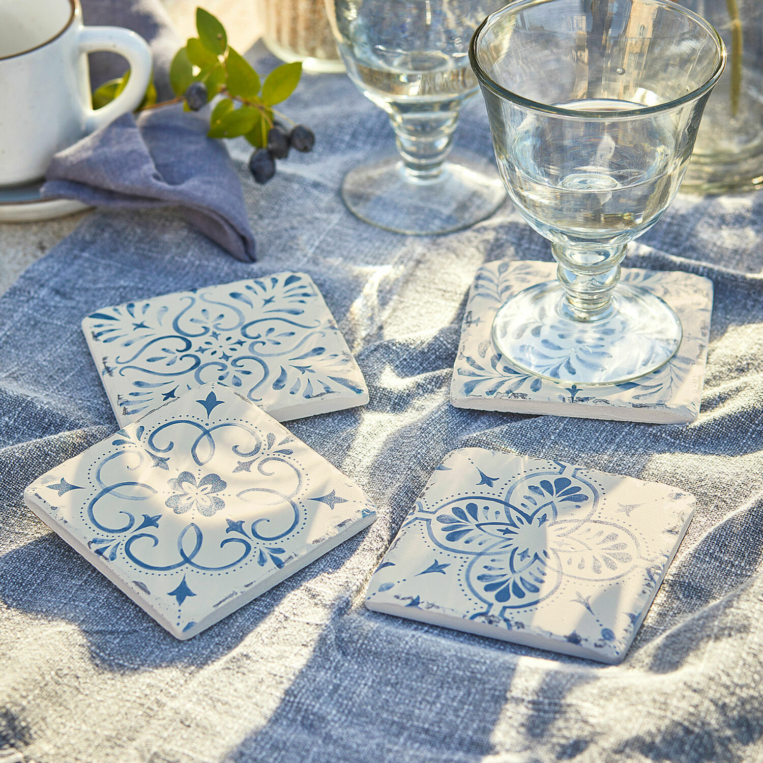 Onderzetter set van 4 Évry Keramische onderzetters met blauw patroon op witte achtergrond op blauwe linnen doek
