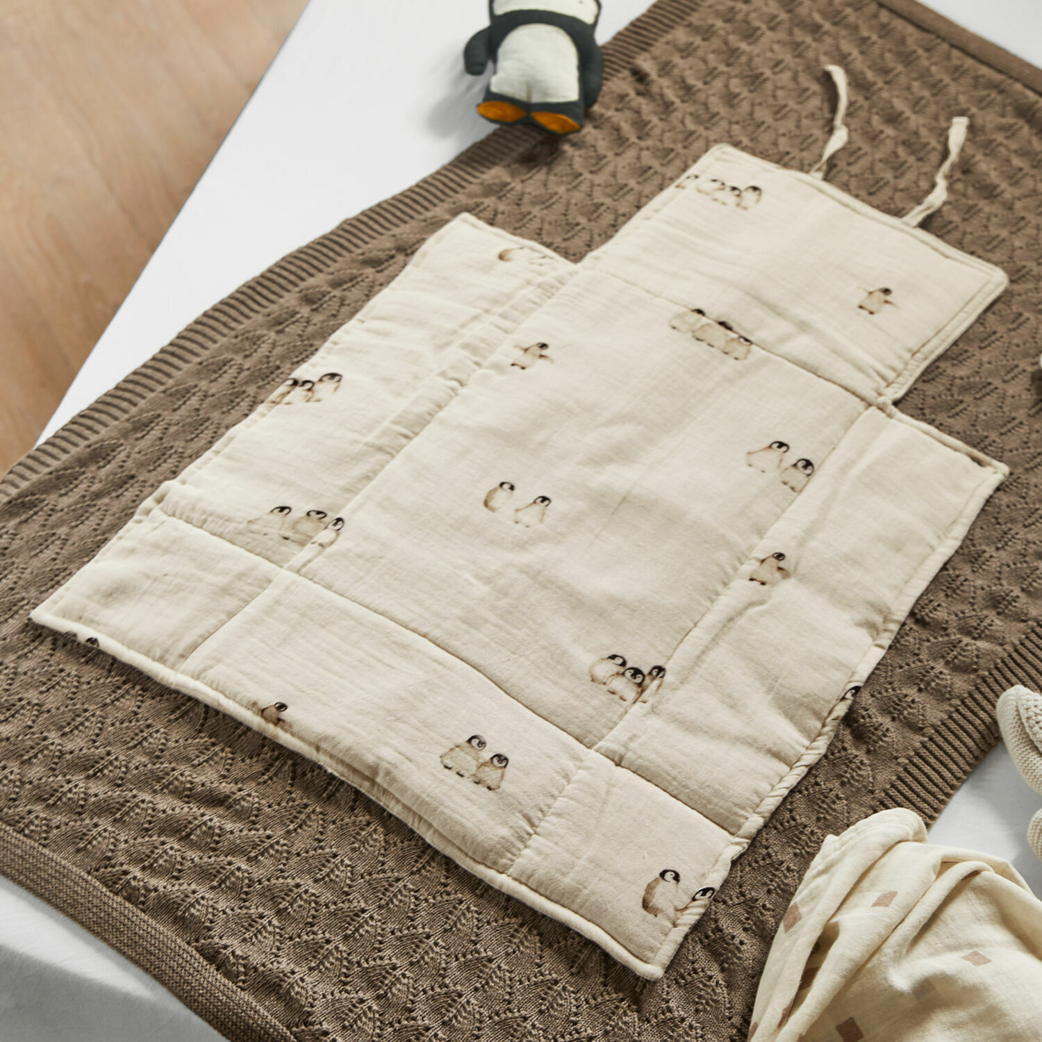 Verschoonkleed Jocienne Beige katoenen baby speelmat met pinguïnprint op bruine gebreide deken, babyaccessoires