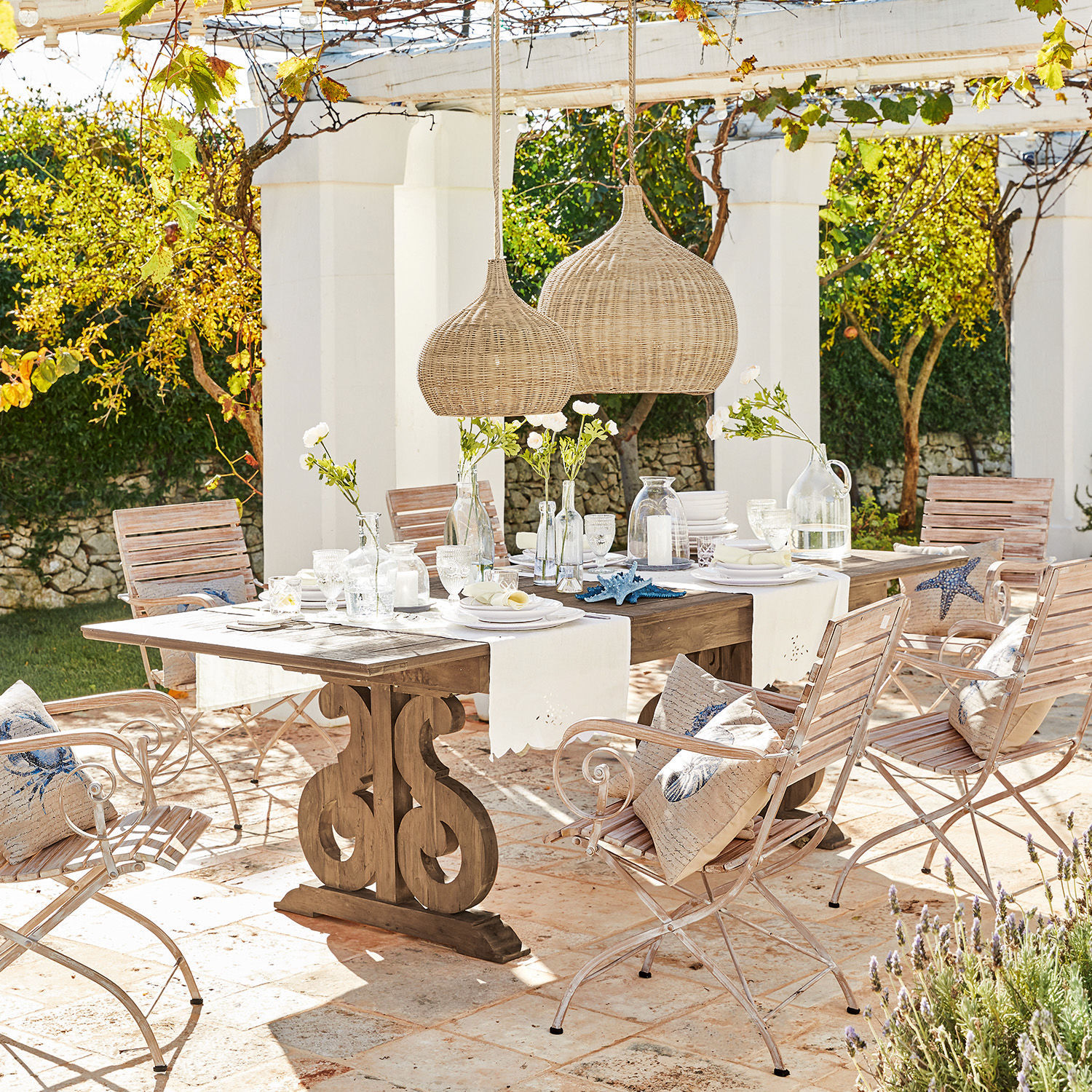 Tafel Concarneau Tuinmeubelset met houten tafel en lichte metalen stoelen op zonnig terras met decoratie