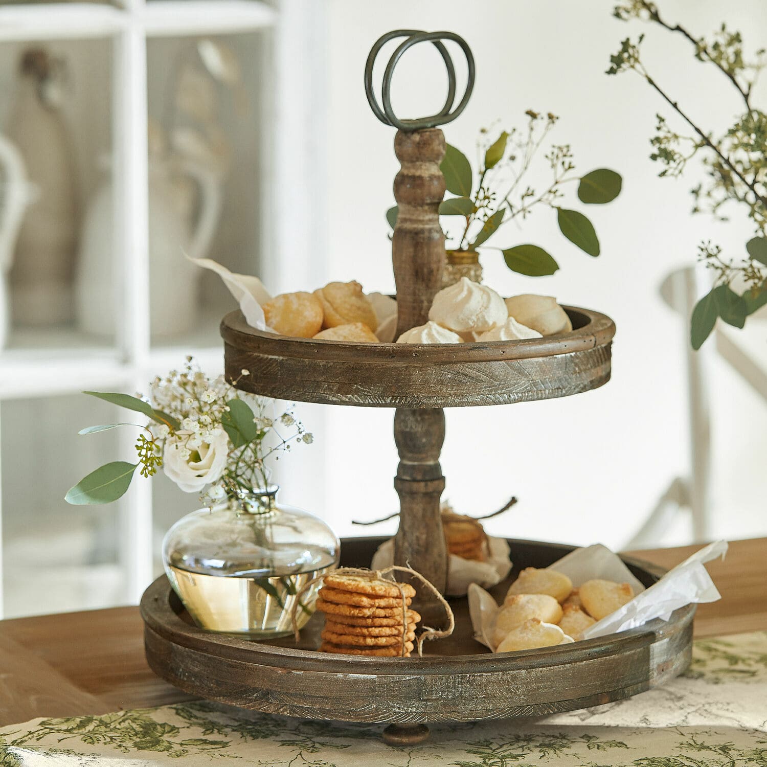 Rustieke tweelaagse houten etagère in bruine kleur met koekjes en bloemen op tafel