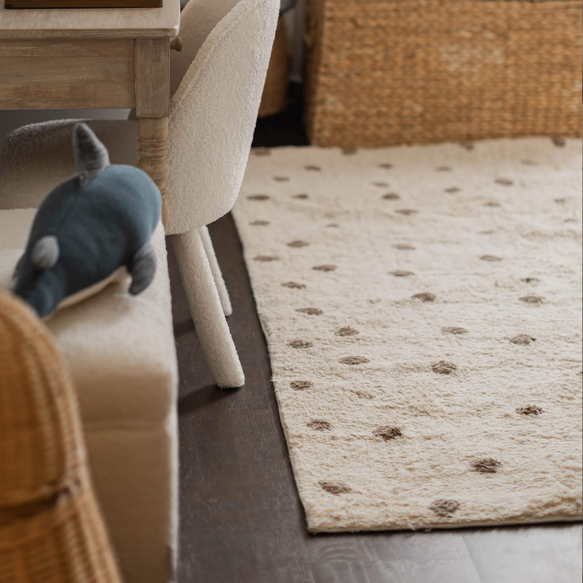 Beige vloerkleed van zacht materiaal met bruine stippen op donkere vloer in woonkamer