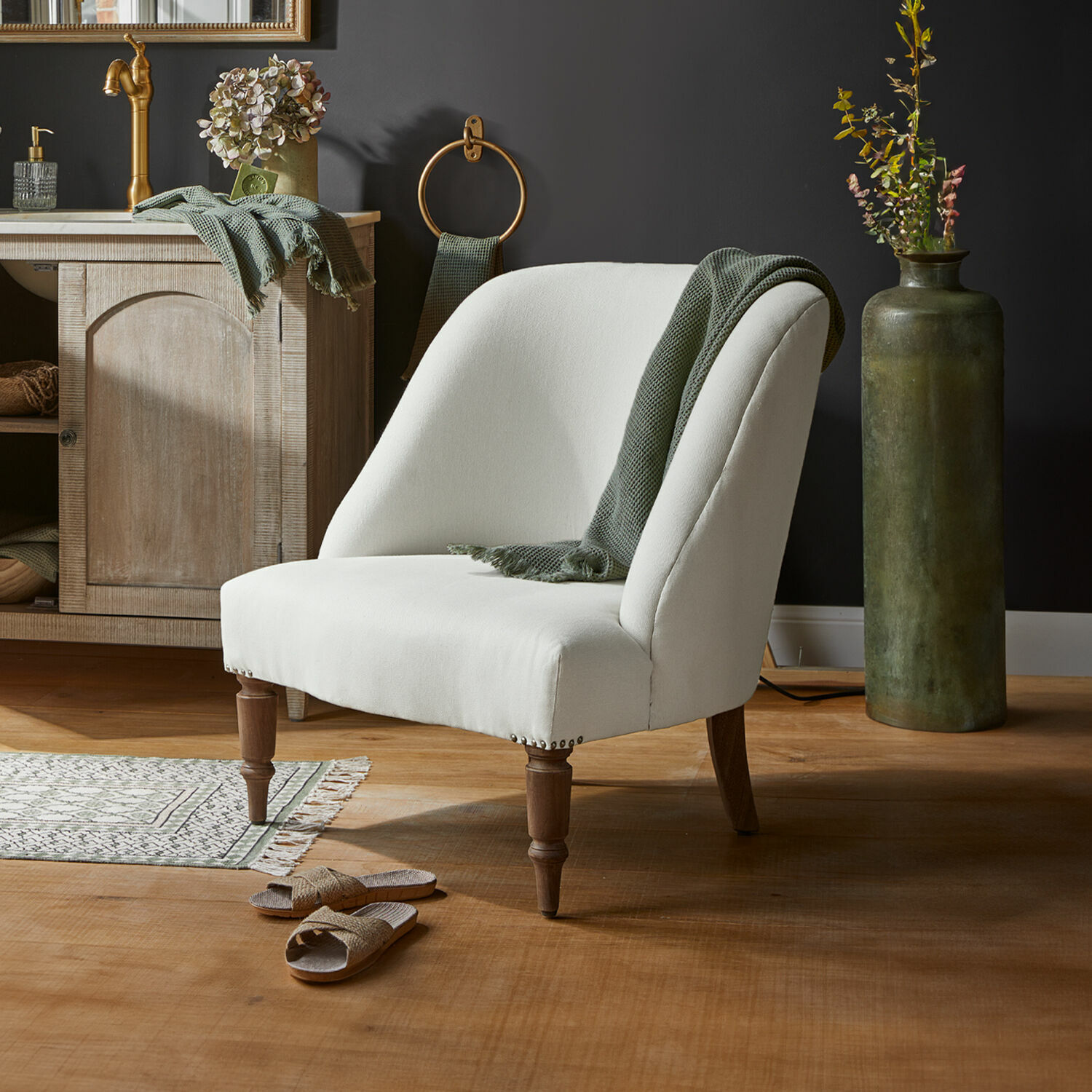 Witte gestoffeerde stoel met houten poten en groene deken in modern interieur