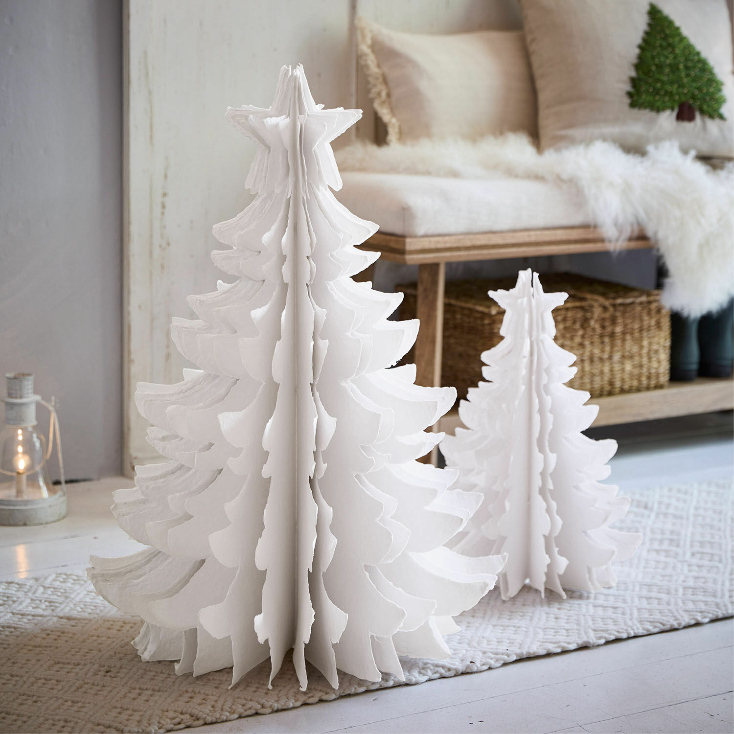 Sierboom set van 2 Amuré Twee witte papieren kerstbomen in verschillende maten op een vloerkleed in een lichte kamer