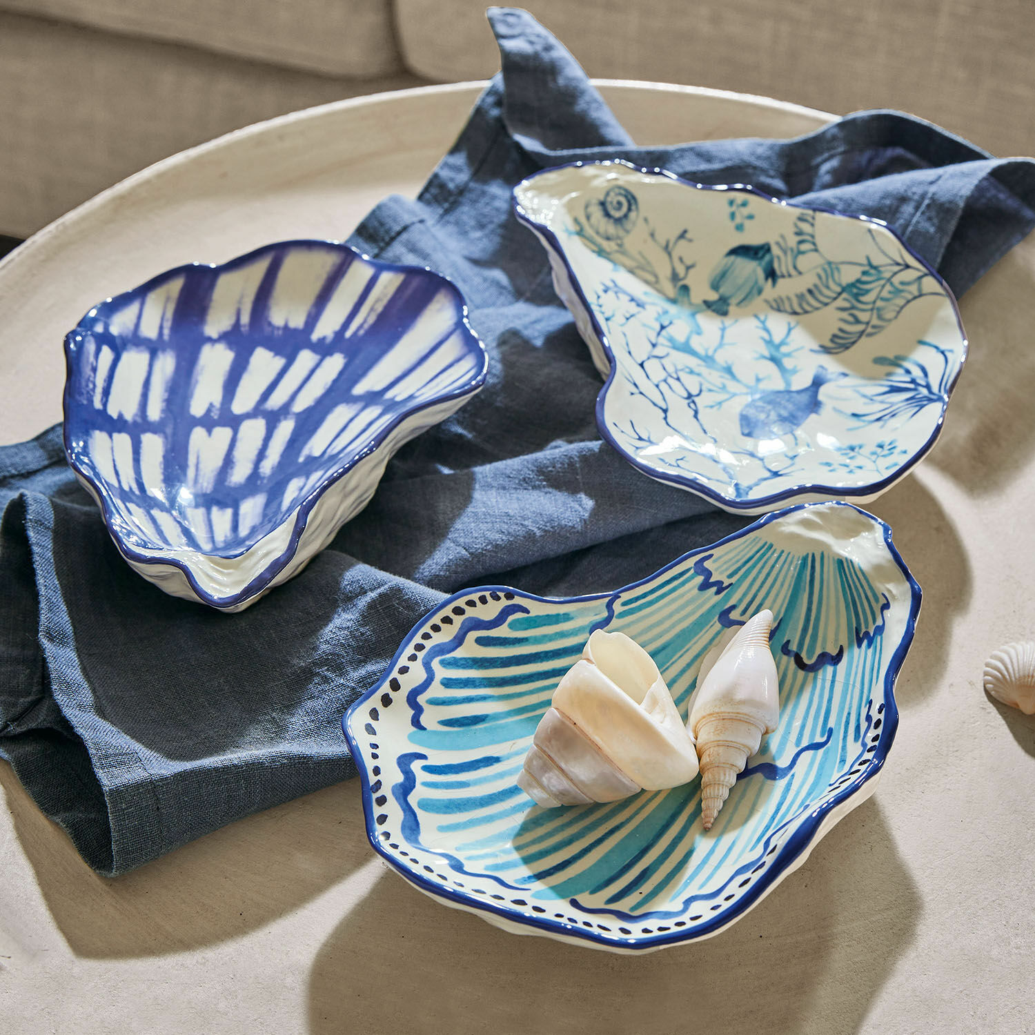 Keramische schaaltjes in schelpvorm met blauw patroon op beige achtergrond, tafeldecoratie