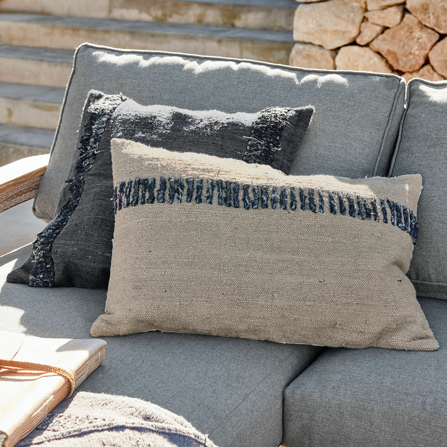 Kussenhoes set van 2 Foix Beige en zwarte decoratieve kussens van stof op grijze buitenbank, woontextiel