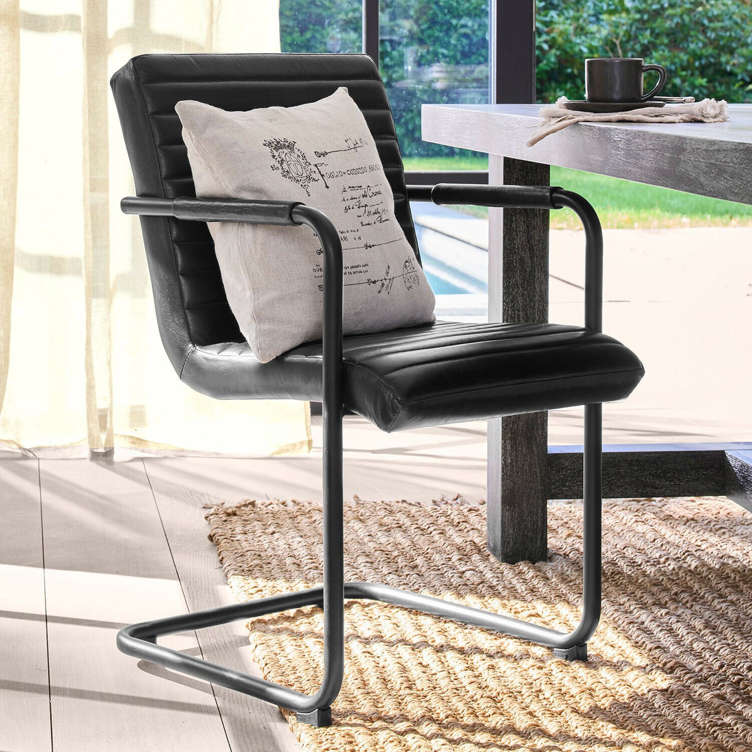 Zwarte stoel van kunstleer met metalen frame en licht kussen, moderne eetkamerstoel