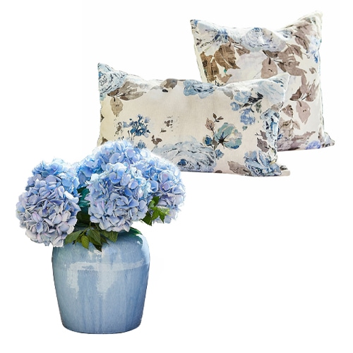 Blauwe hortensia's in blauwe keramische vaas met twee kussens met bloemenpatroon