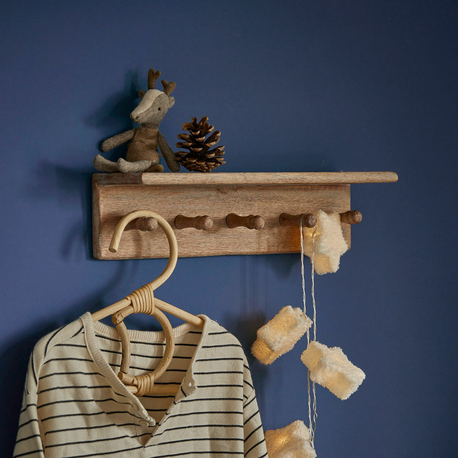 Wandplank Norellan Houten wandkapstok met haken, knuffelrendier en lichtsnoer aan blauwe muur